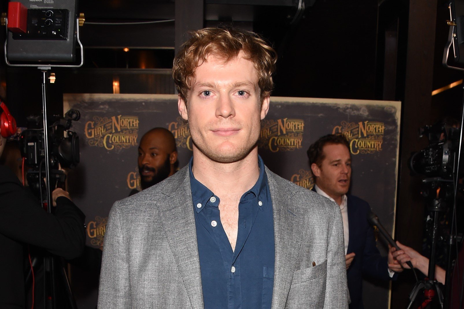 Sam Reid in a blue shirt and gray jacket at the 'Girl from the North Country' afterparty