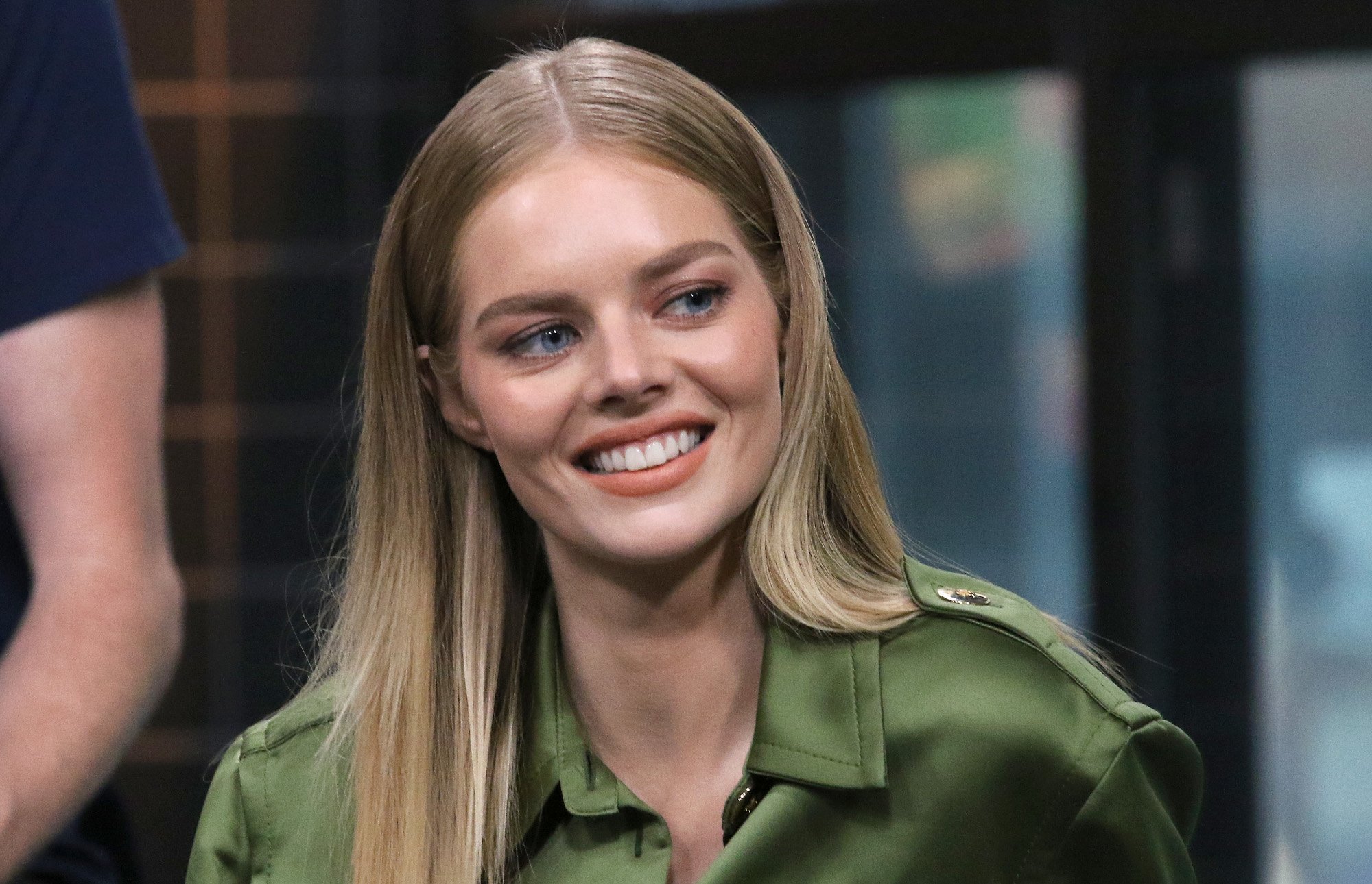 'Nine Perfect Strangers' star Samara Weaving. She's wearing a green button-up blouse and looking to the left of the camera. She's smiling.