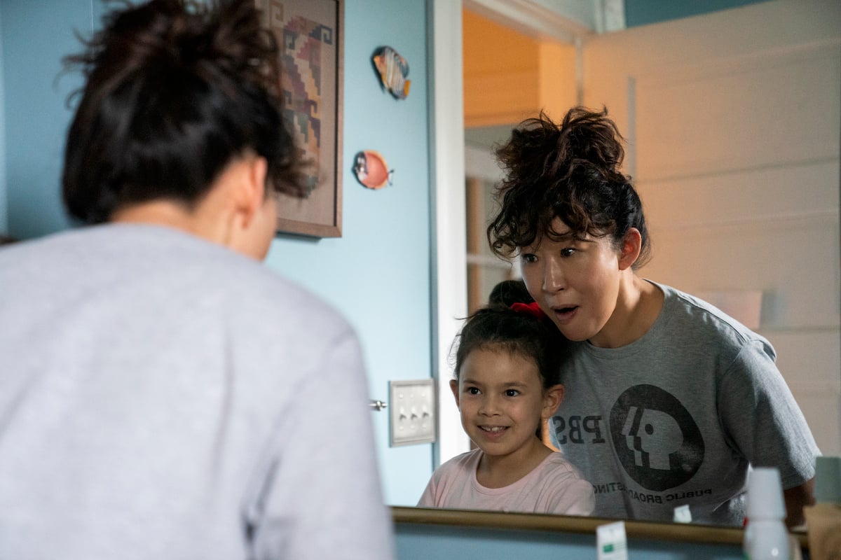 Sandra Oh wears a gray t-shirt and stands in front a bathroom mirror with Everly Carganilla in 'The Chair'