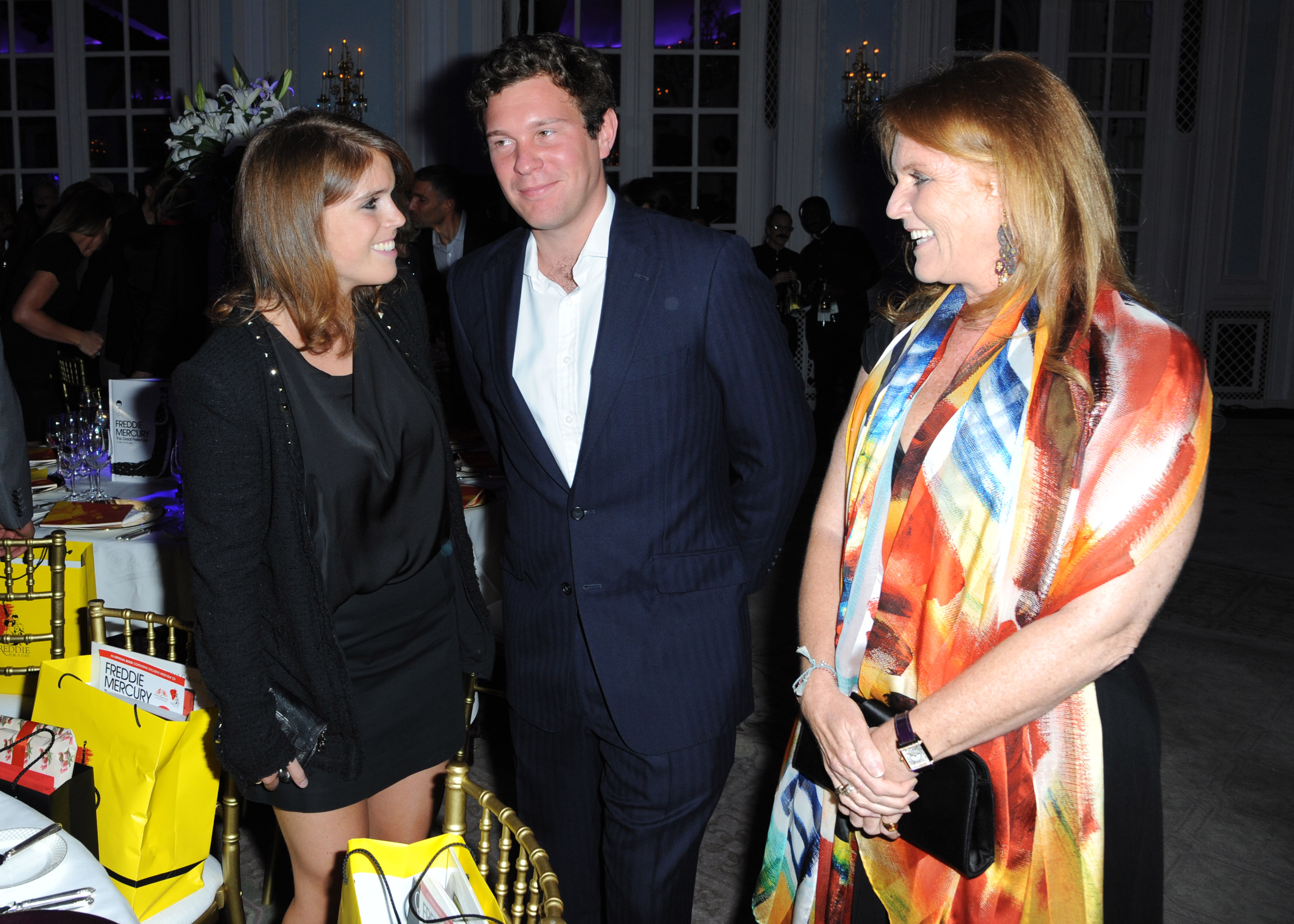 Sarah Ferguson, Jack Brooksbank, and Princess Eugenie standing together at a reception