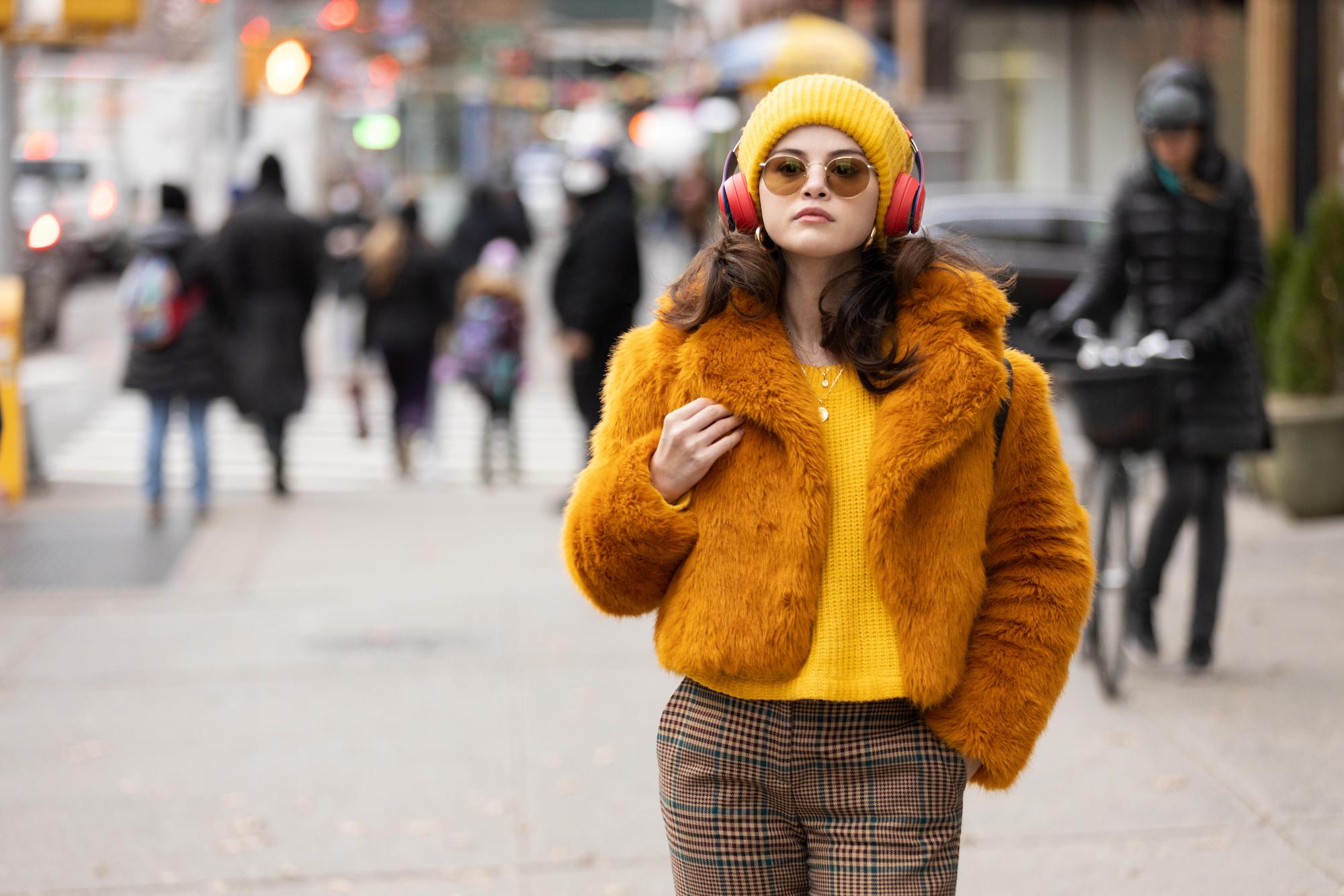 Selena Gomez walks down the street wearing headphones