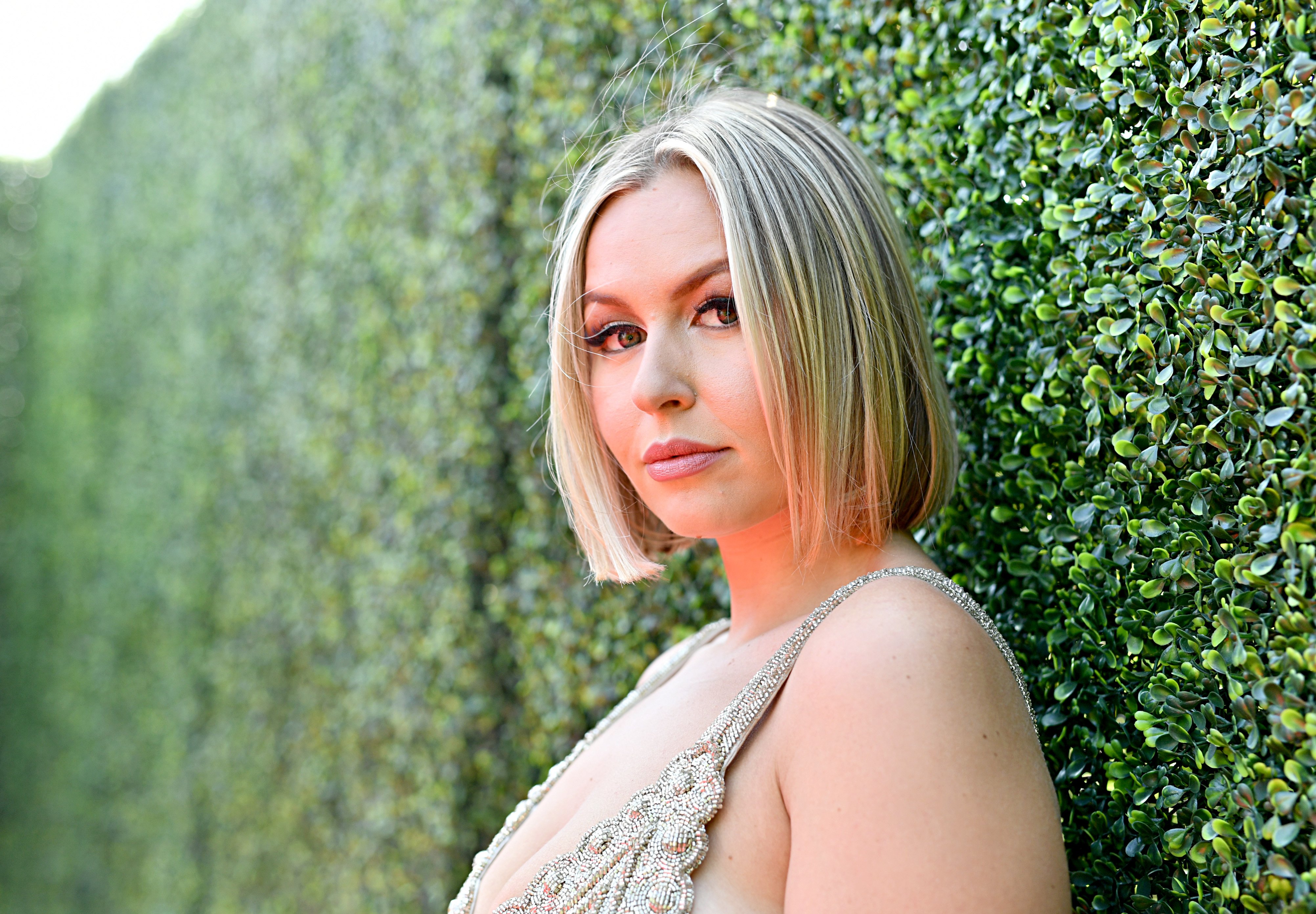 Serena Kerrigan poses in front of a wall of leaves