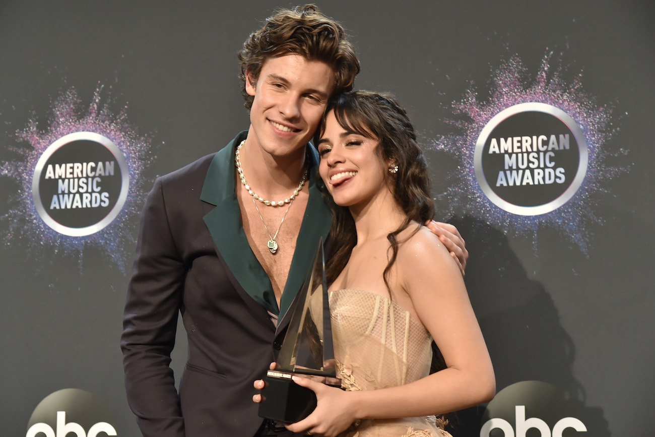 Shawn Mendes and Camila Cabello standing next to each other in front of a gray background