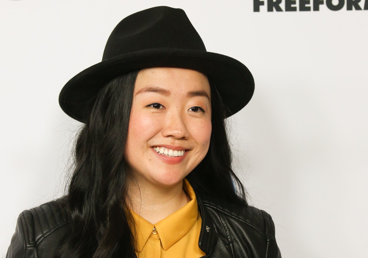 Sherry Cola wears a black hat and smiles while at a media event.