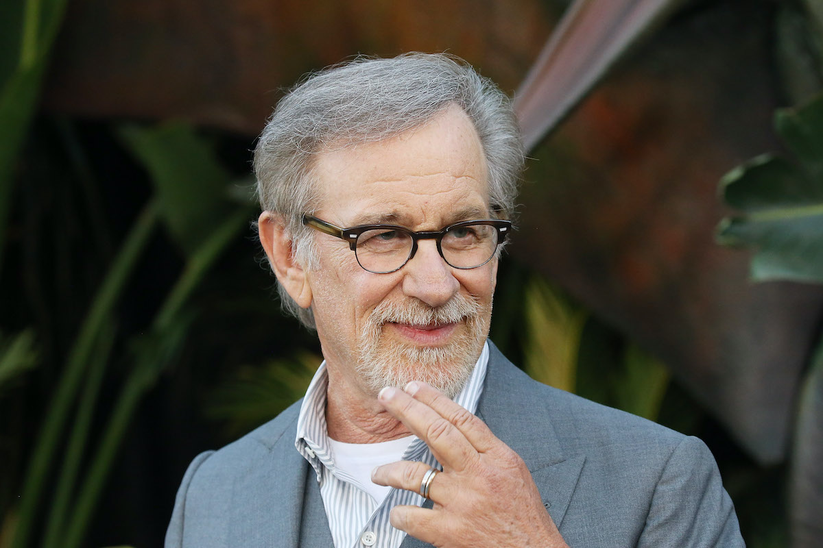 Steven Spielberg smiles and poses in a gray suit