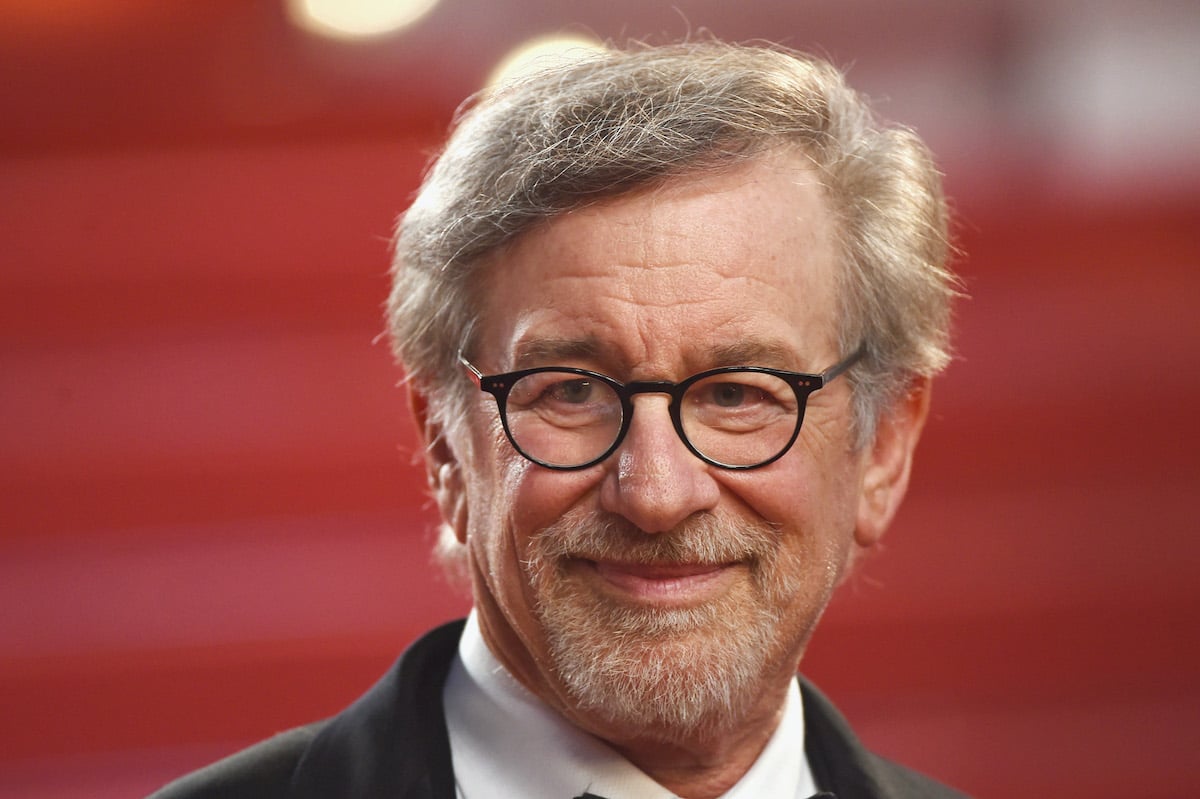 Steven Spielberg smiles amid a red background