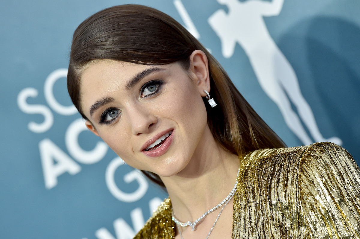 Natalia Dyer of 'Stranger Things' with her hair down and in a gold dress standing in front of sign for the Screen Actors Guild Awards.