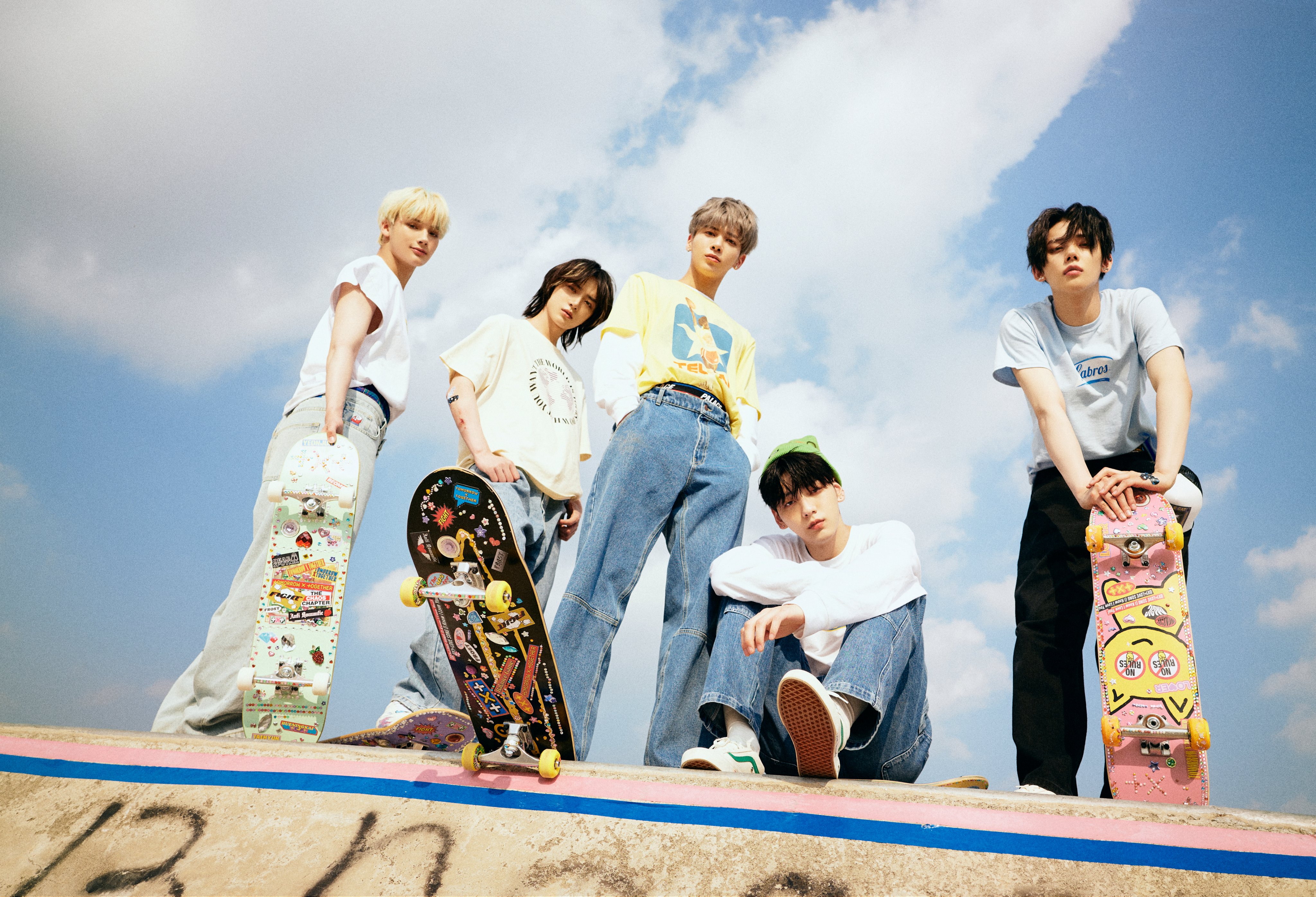 Huening Kai, Beomgyu, Taehyun, Soobin, and Yeonjun of TXT post with skateboards in skate park