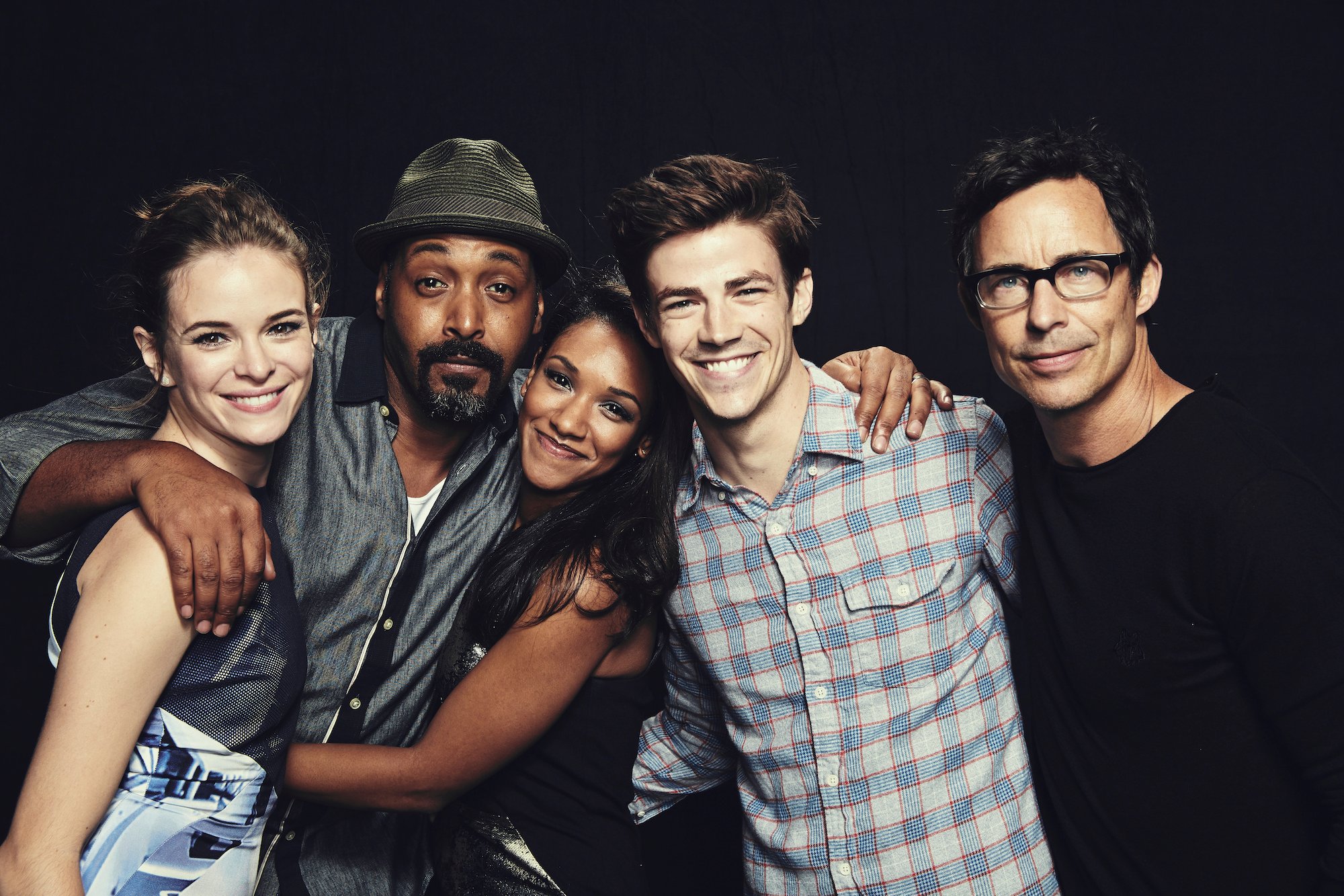 Cast members of 'The Flash' smiling in front of a black curtain