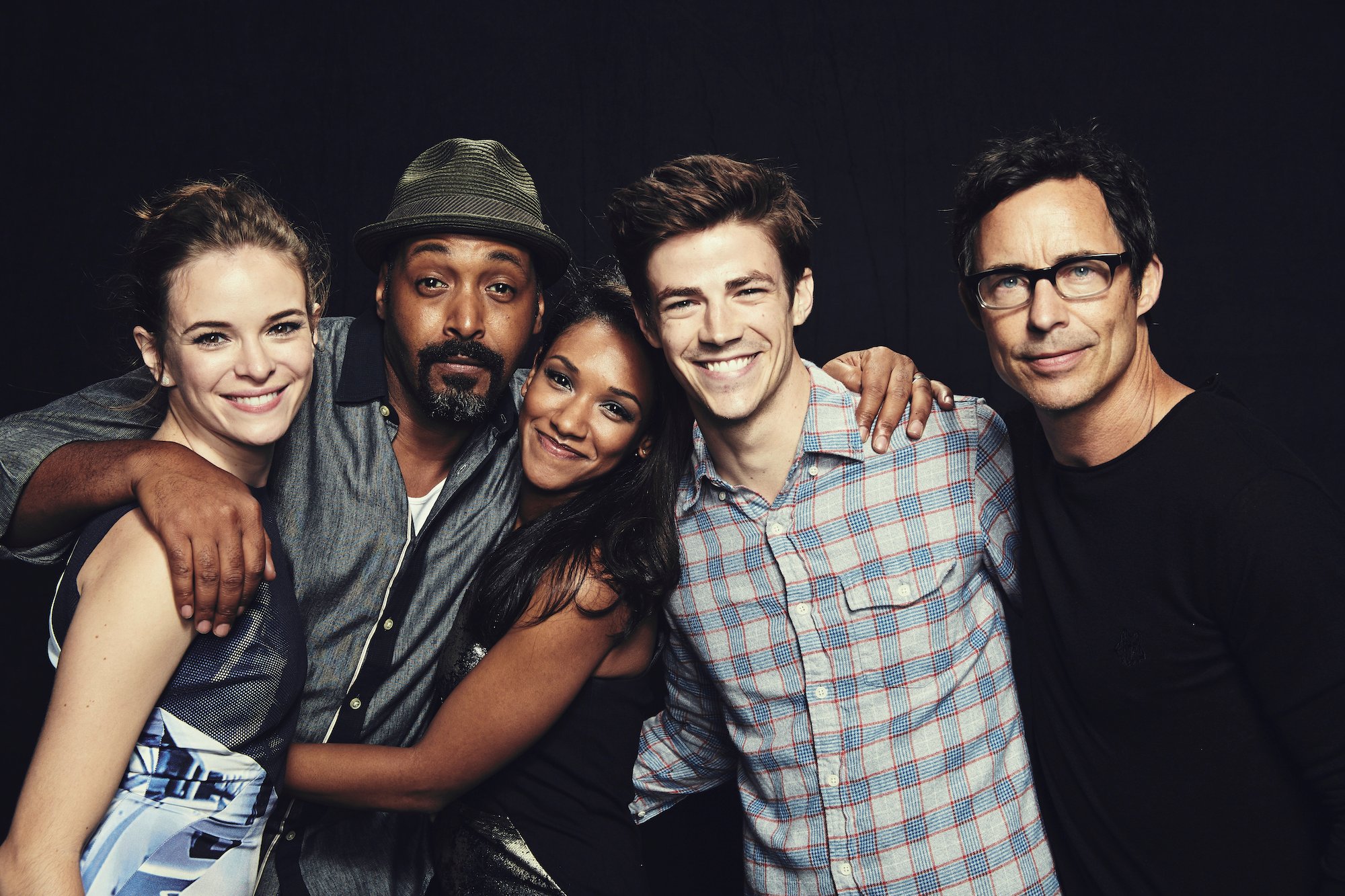 Cast members of 'The Flash' smiling in front of a black curtain