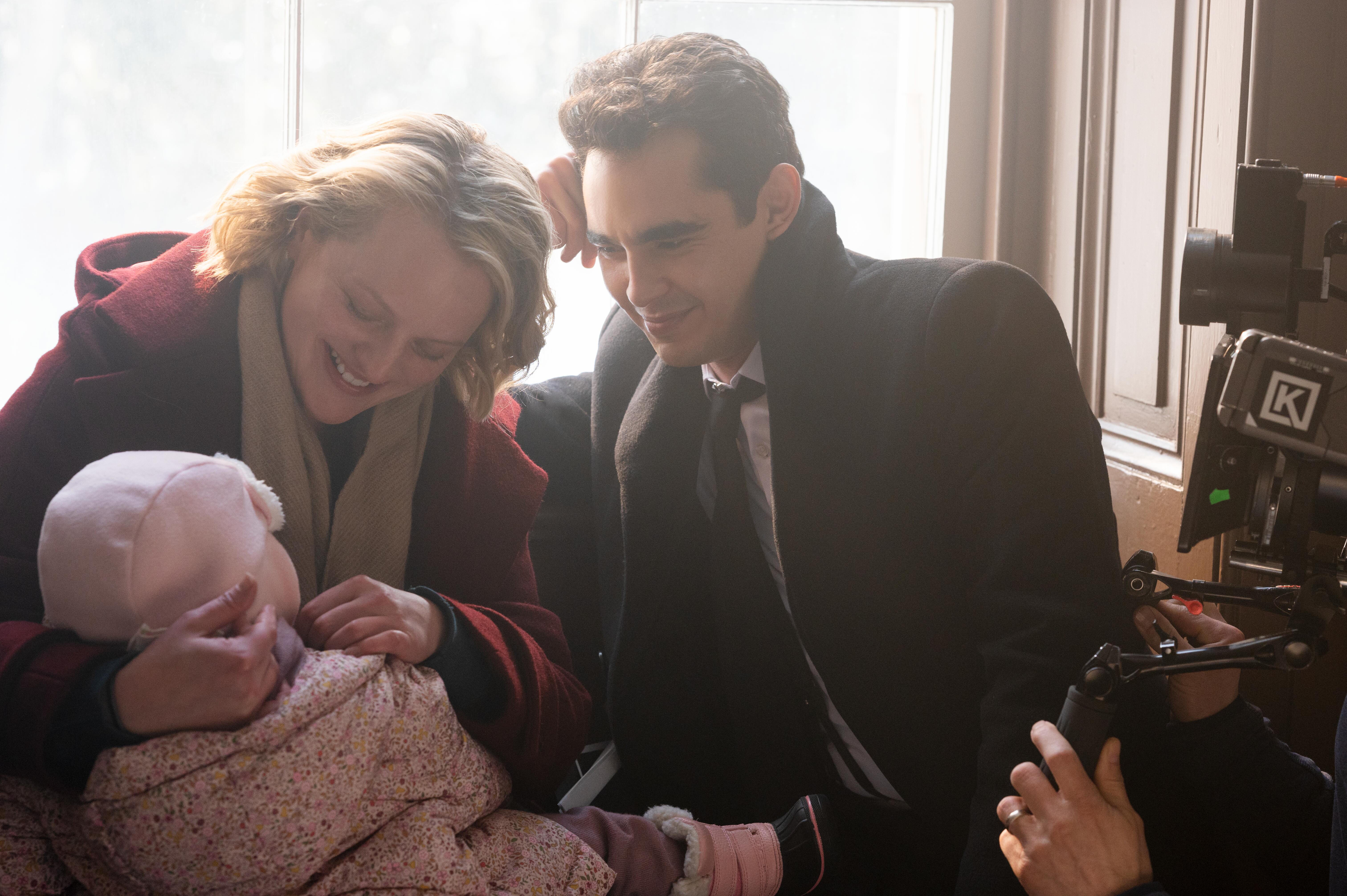 Elisabeth Moss and Max Minghella sit with a baby while filming a scene for 'The Handmaid's Tale'