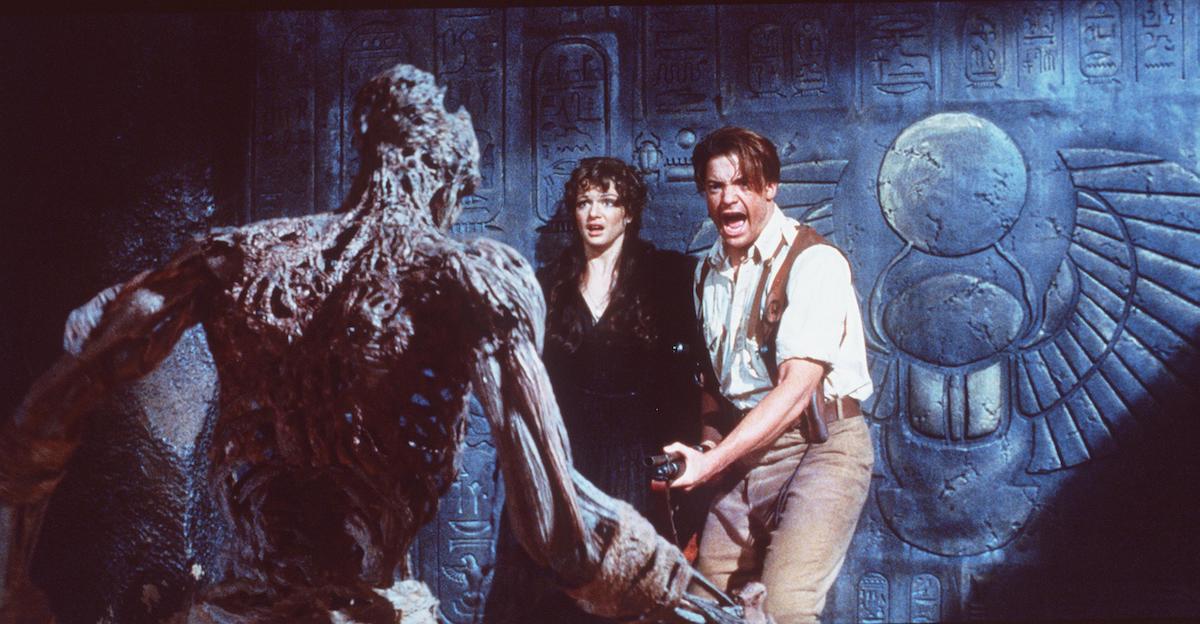 Rick O’Connell (Brendan Fraser) holds a shotgun as the mummy approaches he and Evelyn (Rachel Weisz) in 1999’s ‘The Mummy’