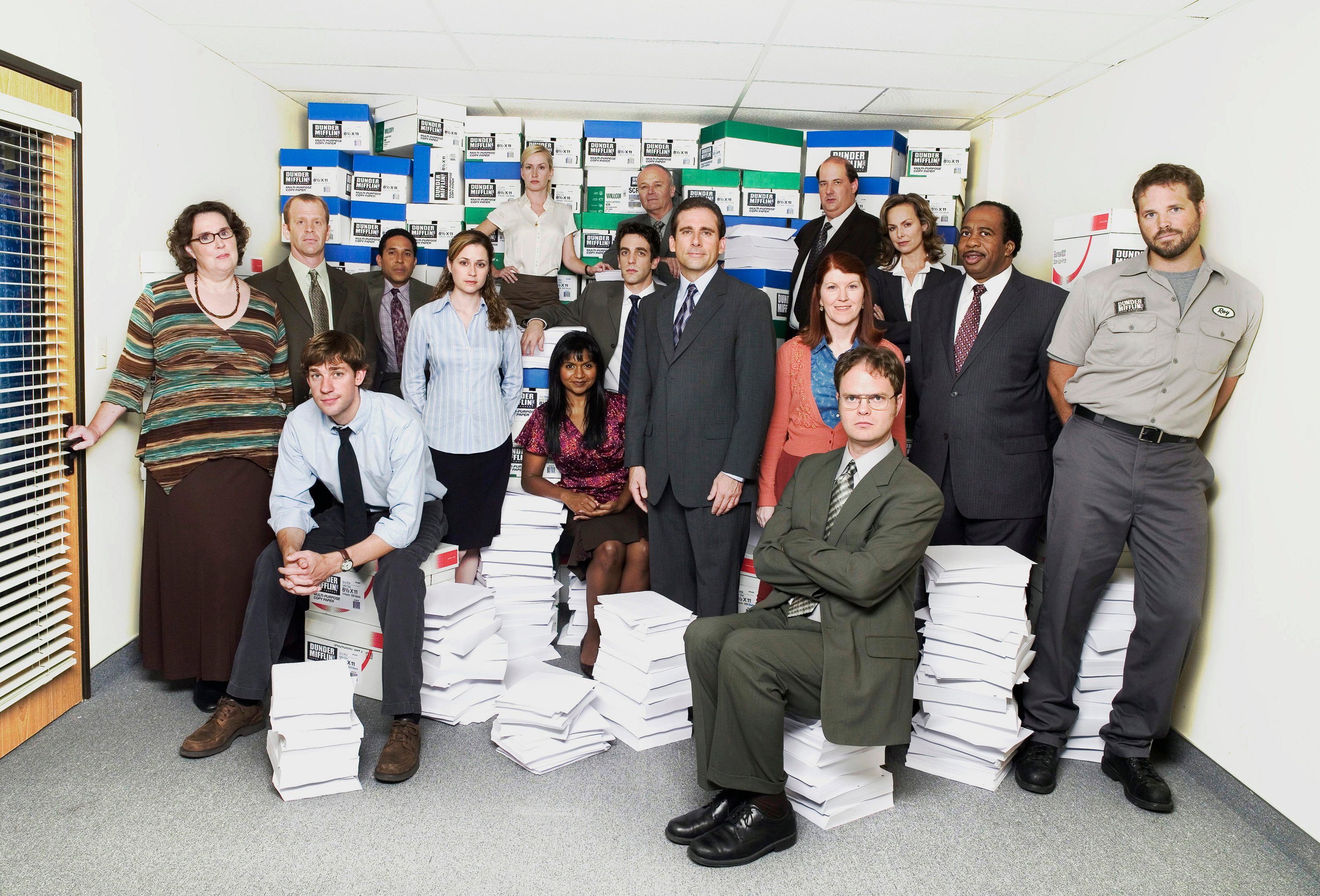 The cast of "The Office' – one of the premier comedy shows – poses for a photo around stacks if Dunder Mifflin paper