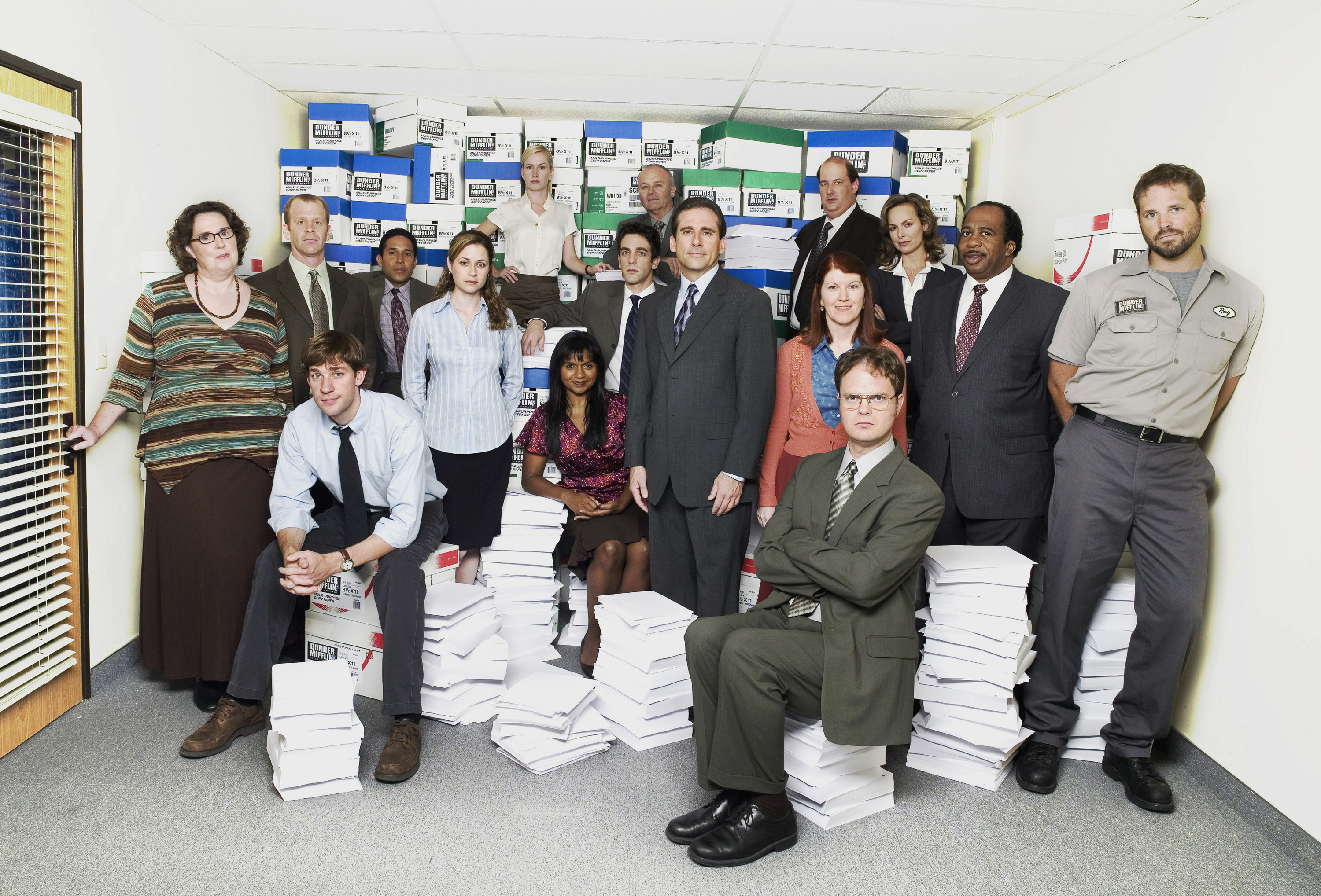 The cast of "The Office' – one of the premier comedy shows – poses for a photo around stacks if Dunder Mifflin paper