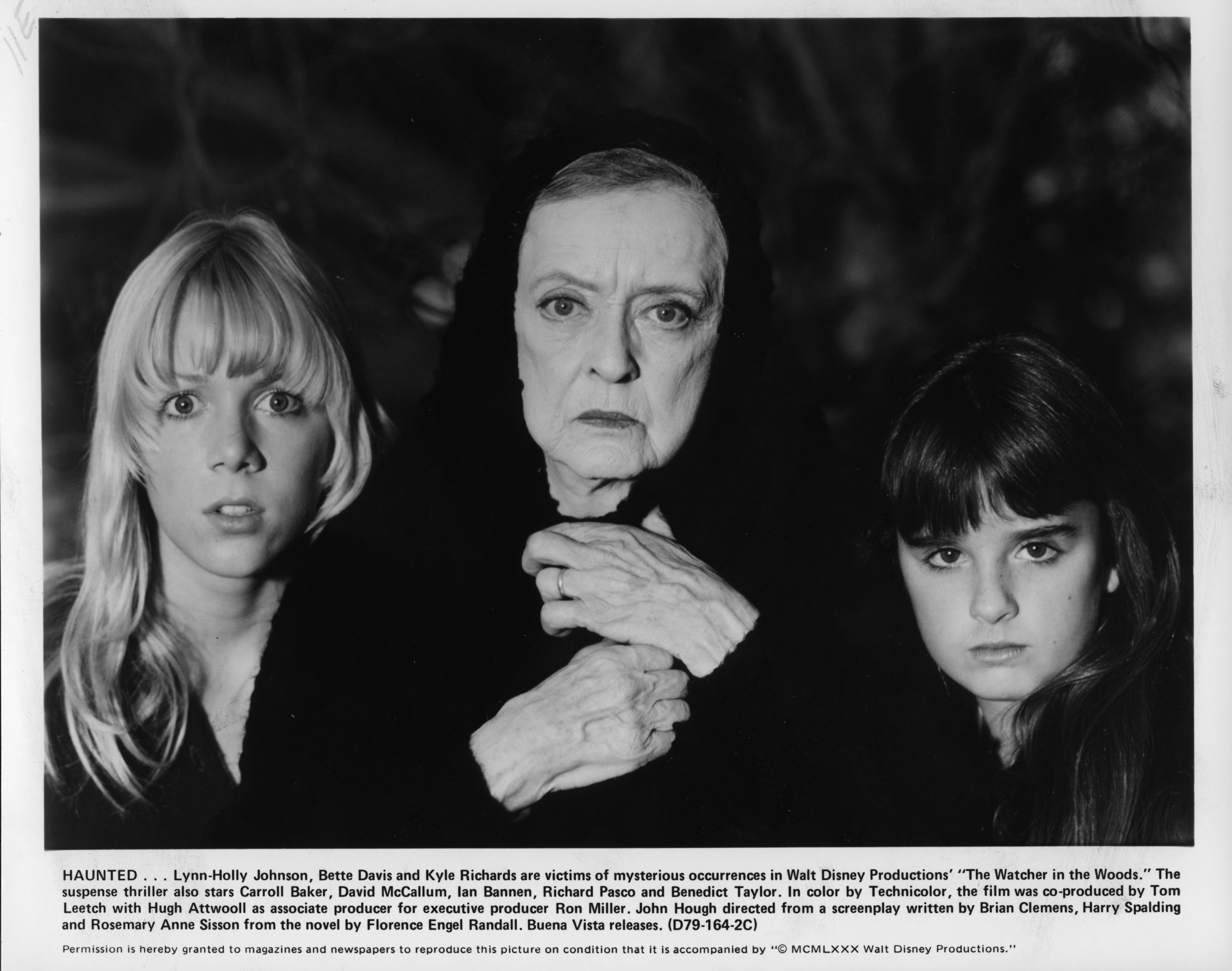 Lynn-Holly Johnson, Bette Davis, and Kyle Richards stare at the camera in a black and white still from 80s movie 'The Watcher in the Woods.'