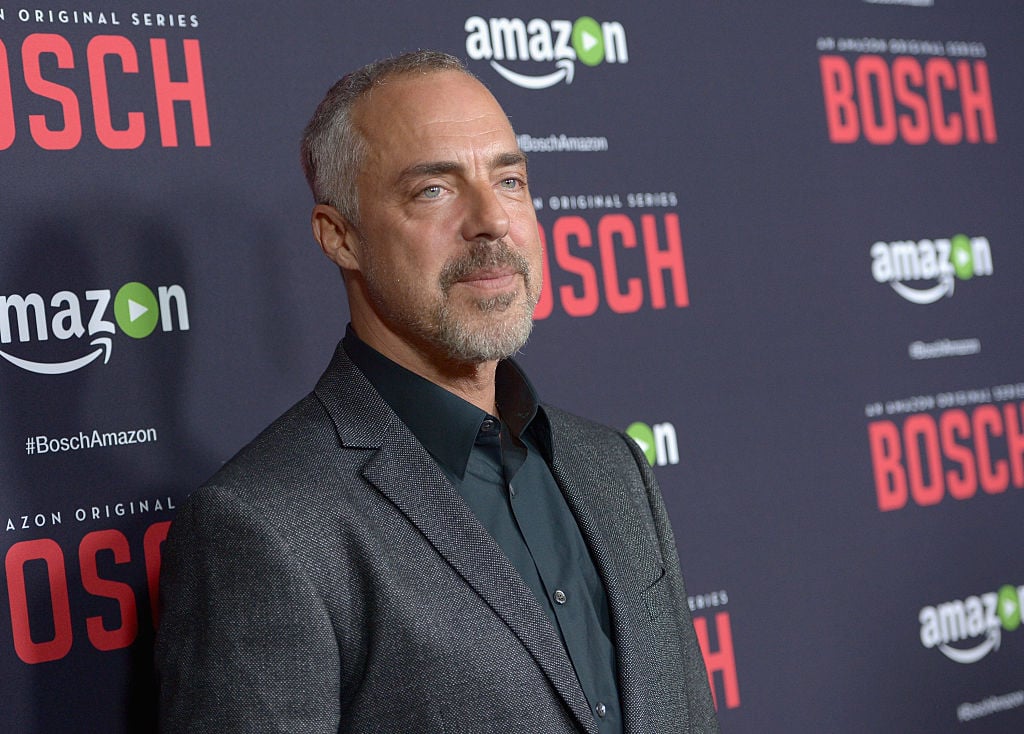 Titus Welliver walks the red carpet in a dark suit. The 'Bosch' title is on the wall behind him.