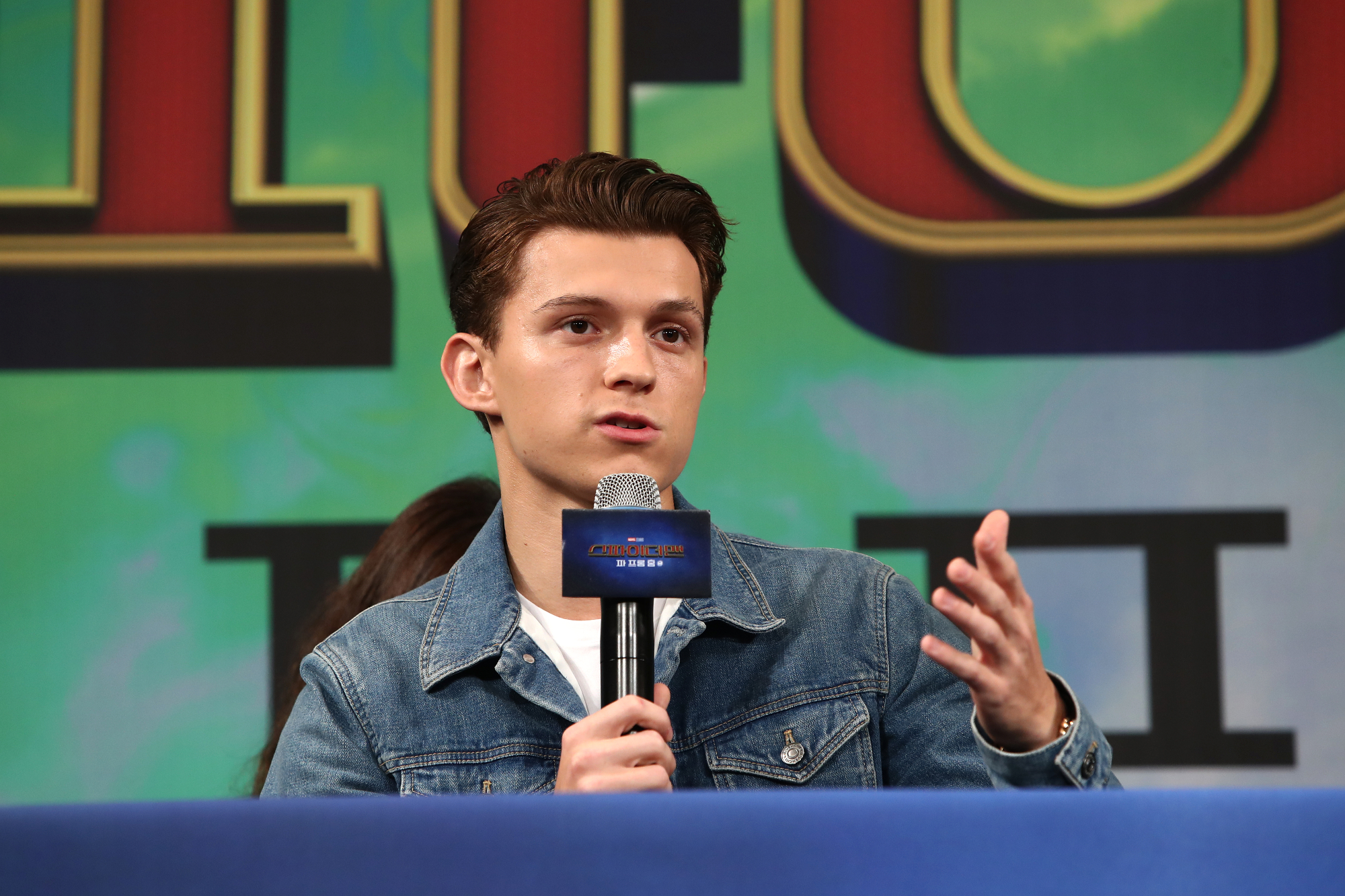 Tom Holland talks into microphone at MCU 'Spider-Man: Far From Home' event