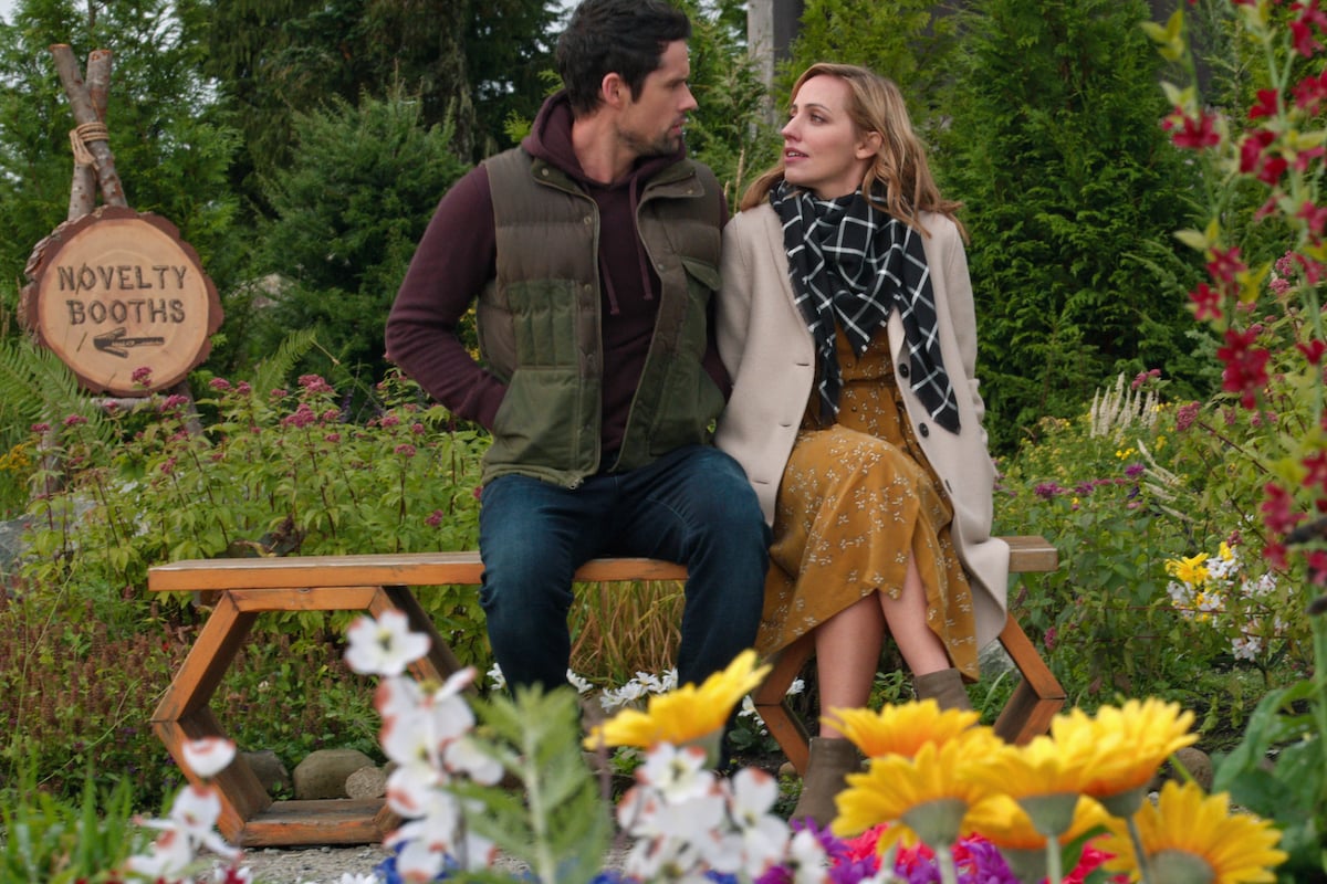 Ben Hollingsworth as Dan Brady and Zibby Allen as Brie Sheridan sitting on a park bench in 'Virgin River'