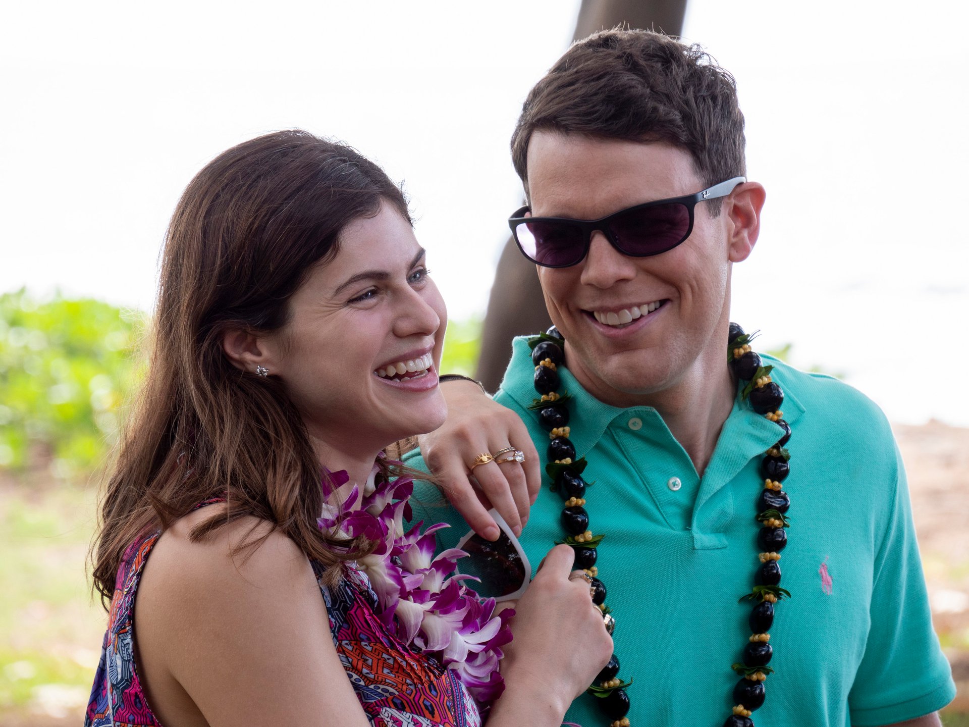 Alexandra Daddario and Jake Lacy on 'The White Lotus.' Daddario, on the left, smiles while leaning on Lacy. Lacy is wearing sunglasses and a turquoise polo and looking at her, smiling.