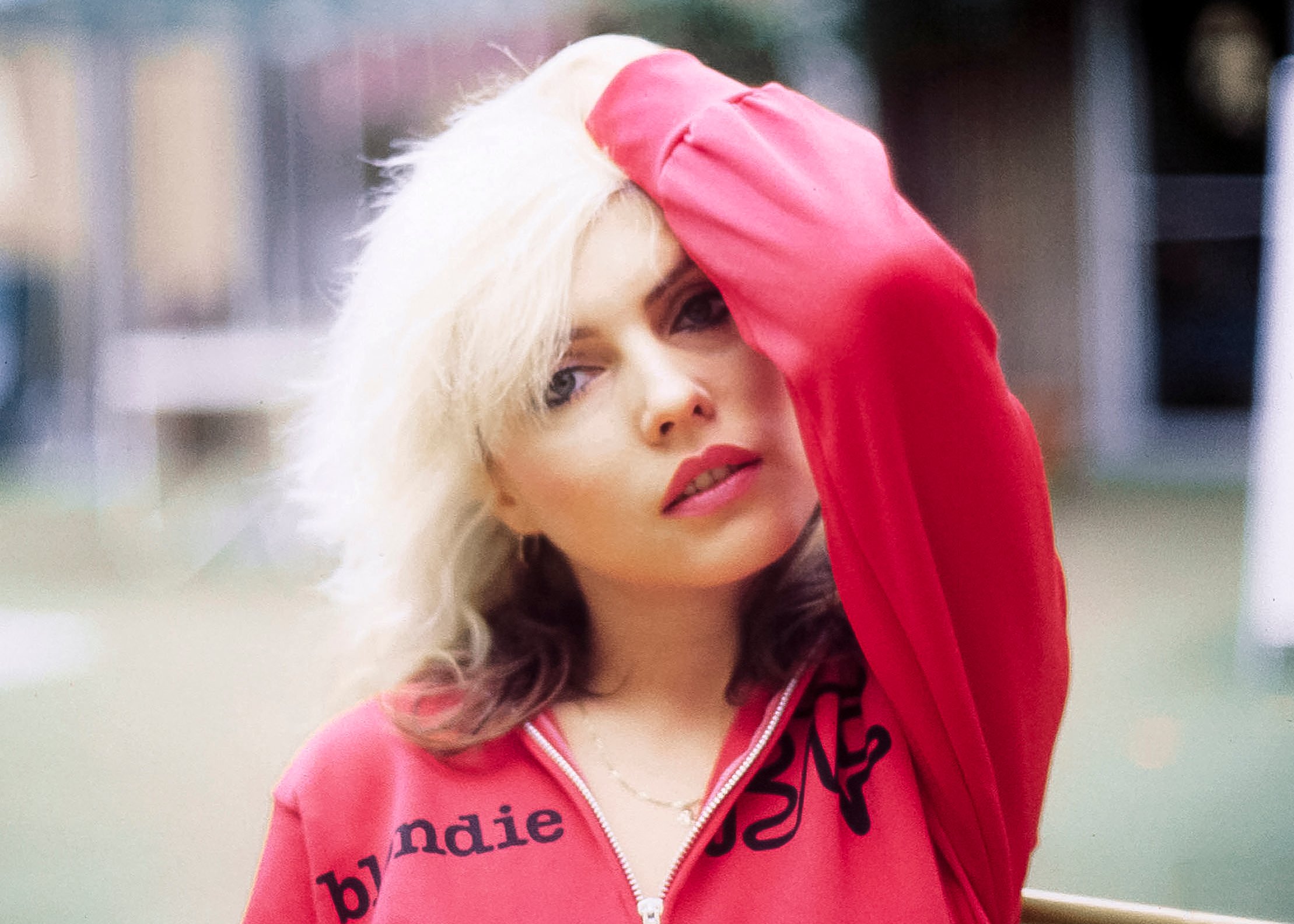 Debbie Harry of Blondie wearing pink and running her fingers through her hair