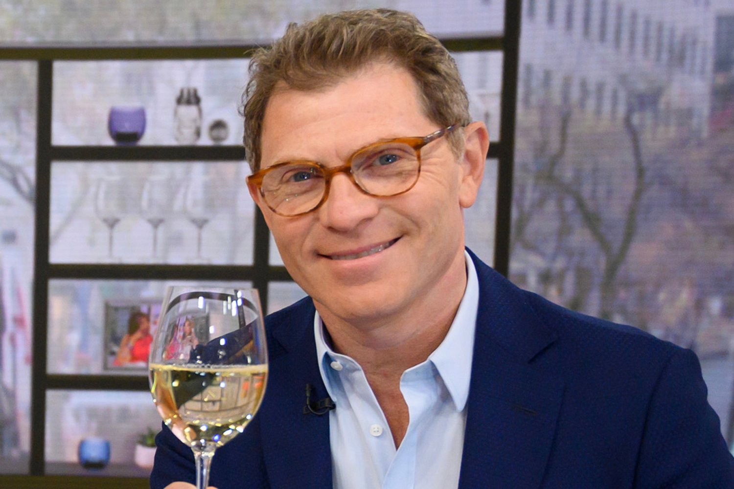 Bobby Flay wearing glasses and holding a wine glass