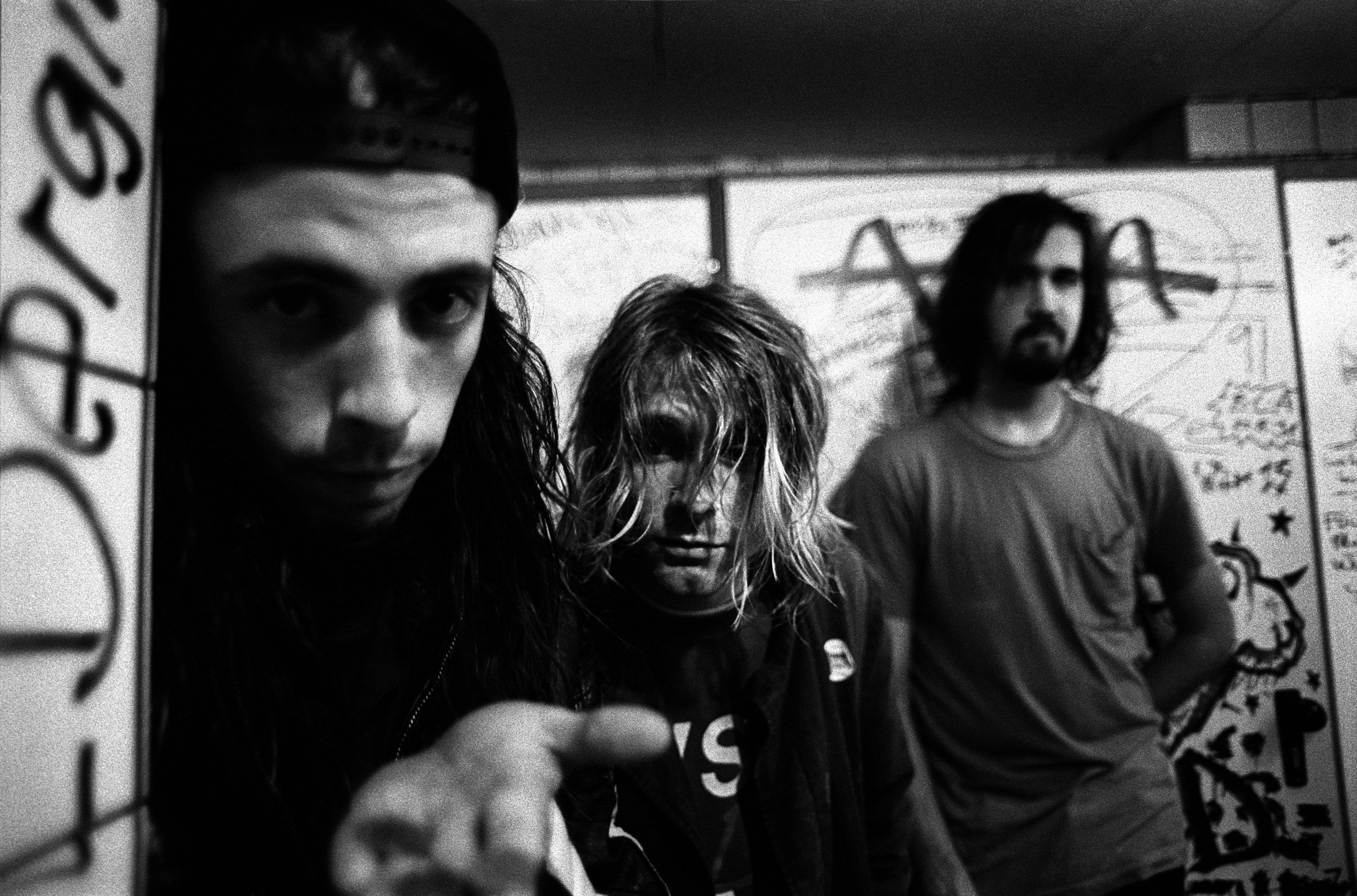 Nirvana's Dave Grohl, Kurt Cobain, and Krist Novoselic near graffiti