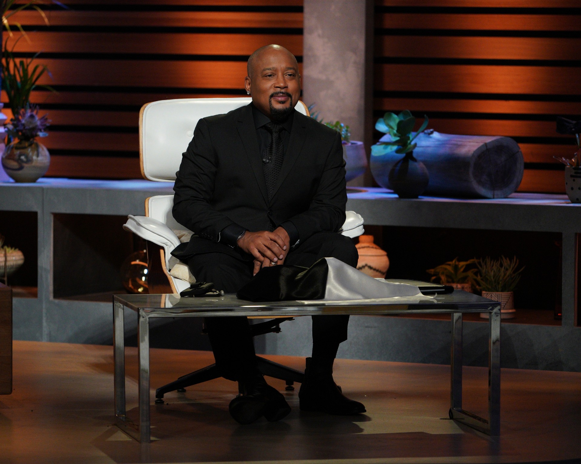 Daymond John sits in a chair on the set of Shark Tank
