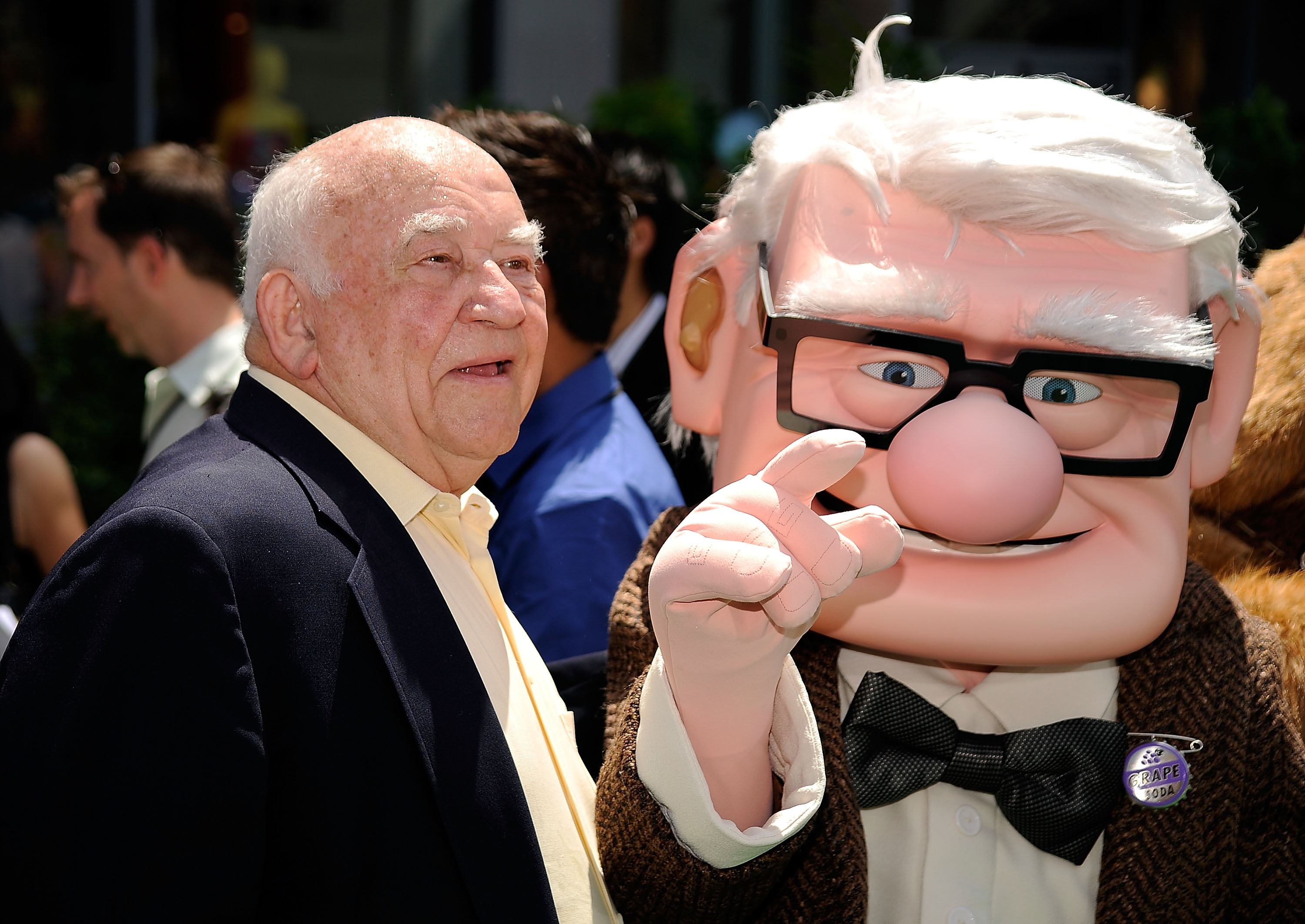 Ed Asner standing next to the character he voiced in the movie 'Up'