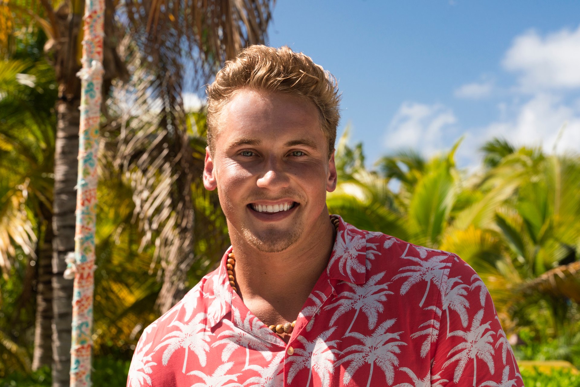 Garrett Morosky in a coral and white tropical shirt looking at the camera for an 'FBoy Island' bio photo.