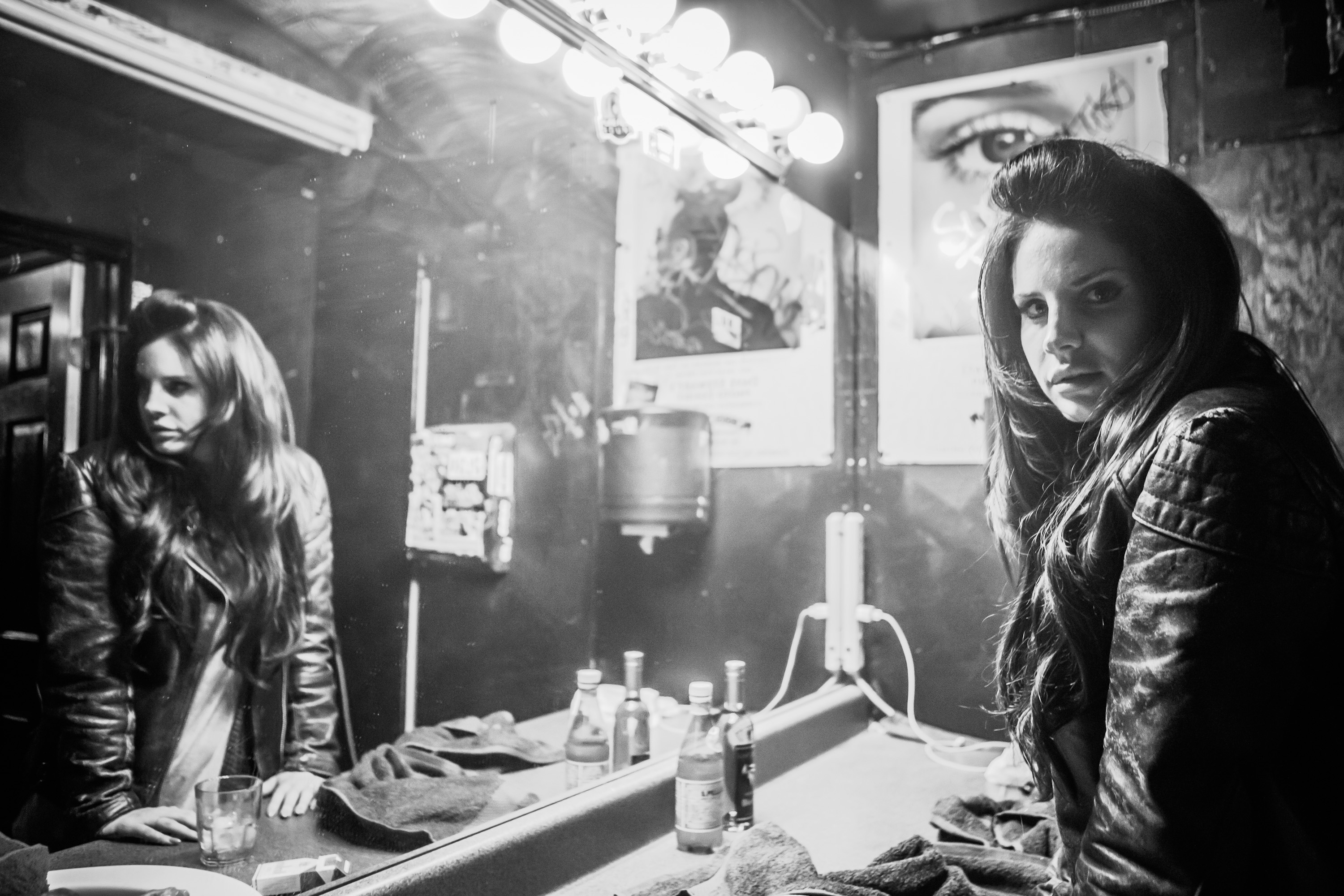 Lana Del Rey wearing a jacket and standing in front of a mirror