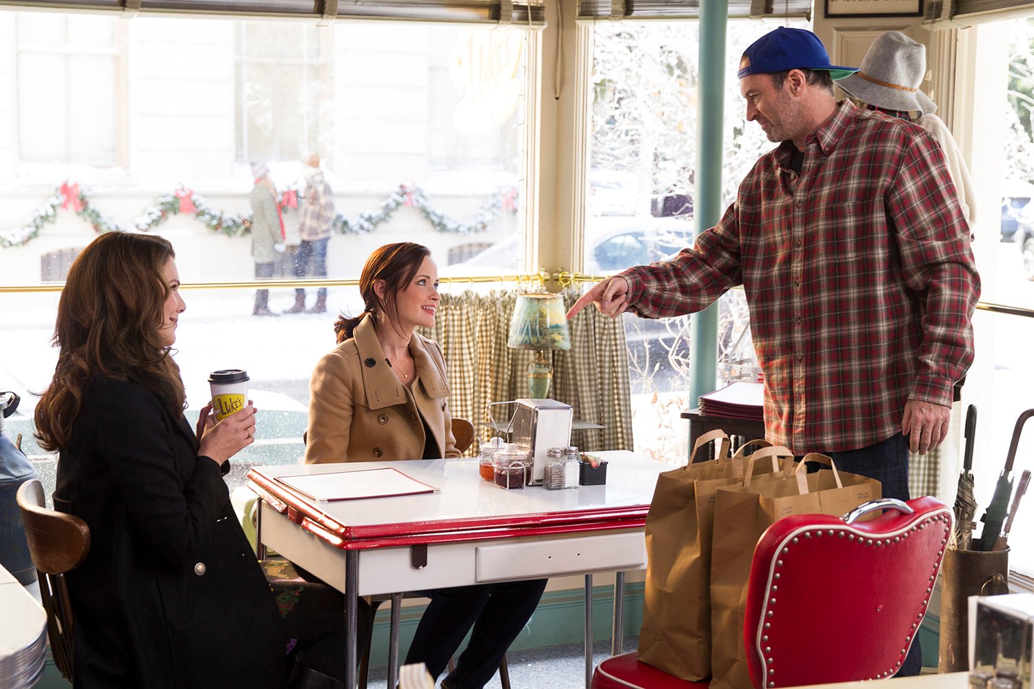 Lauren Graham as Lorelai GIlmore, Alexis Bledel as Rory Gilmore, and Scott Patterson as Luke Danes at Luke's Diner in 'Gilmore Girls' Luke and Lorelai's relationship is at the center of several 'Gilmore Girls' unpopular opinions