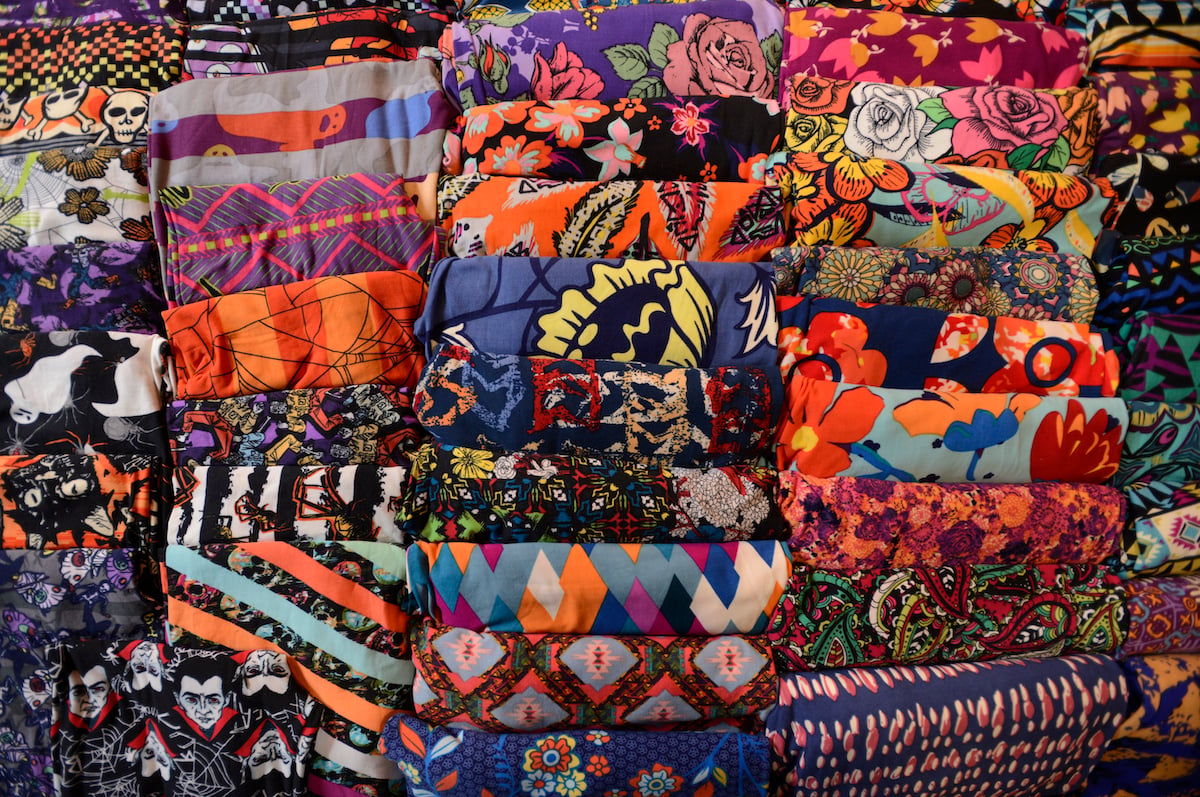 Stacks of colorfully printed LuLaRooe leggings folded neatly in rows.