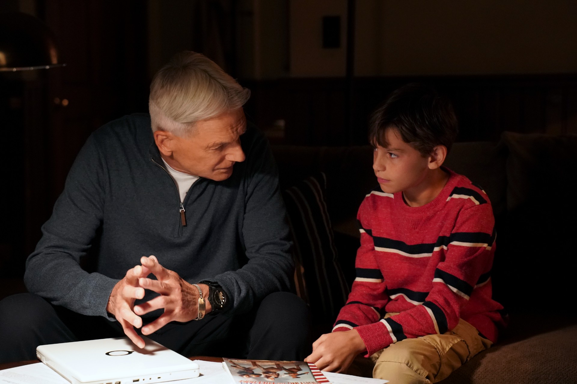 Mark Harmon and Jack Fisher sit on the couch during NCIS