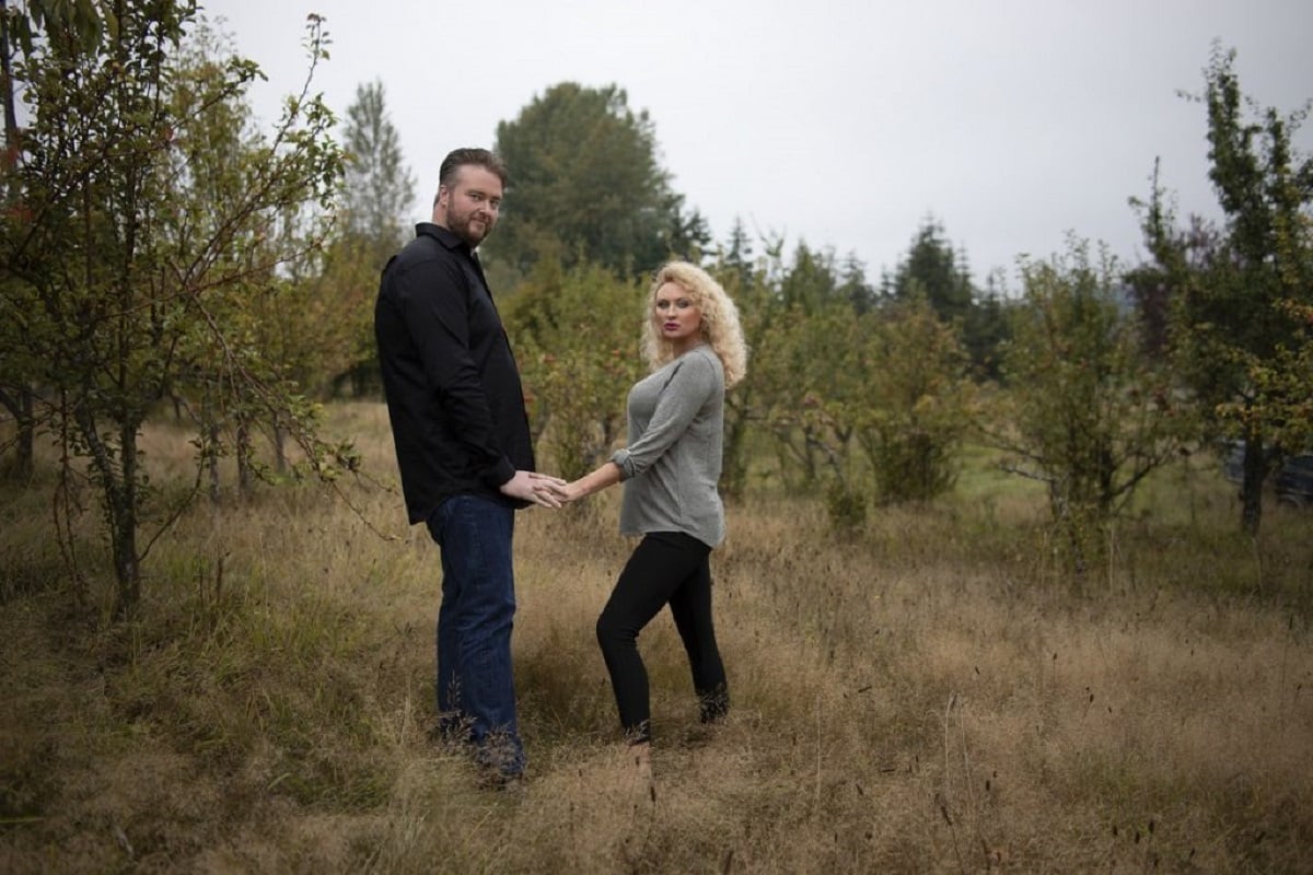 ’90 Day Fiancé’ couple Mike and Natalie hold hands and look at the camera in a field.
