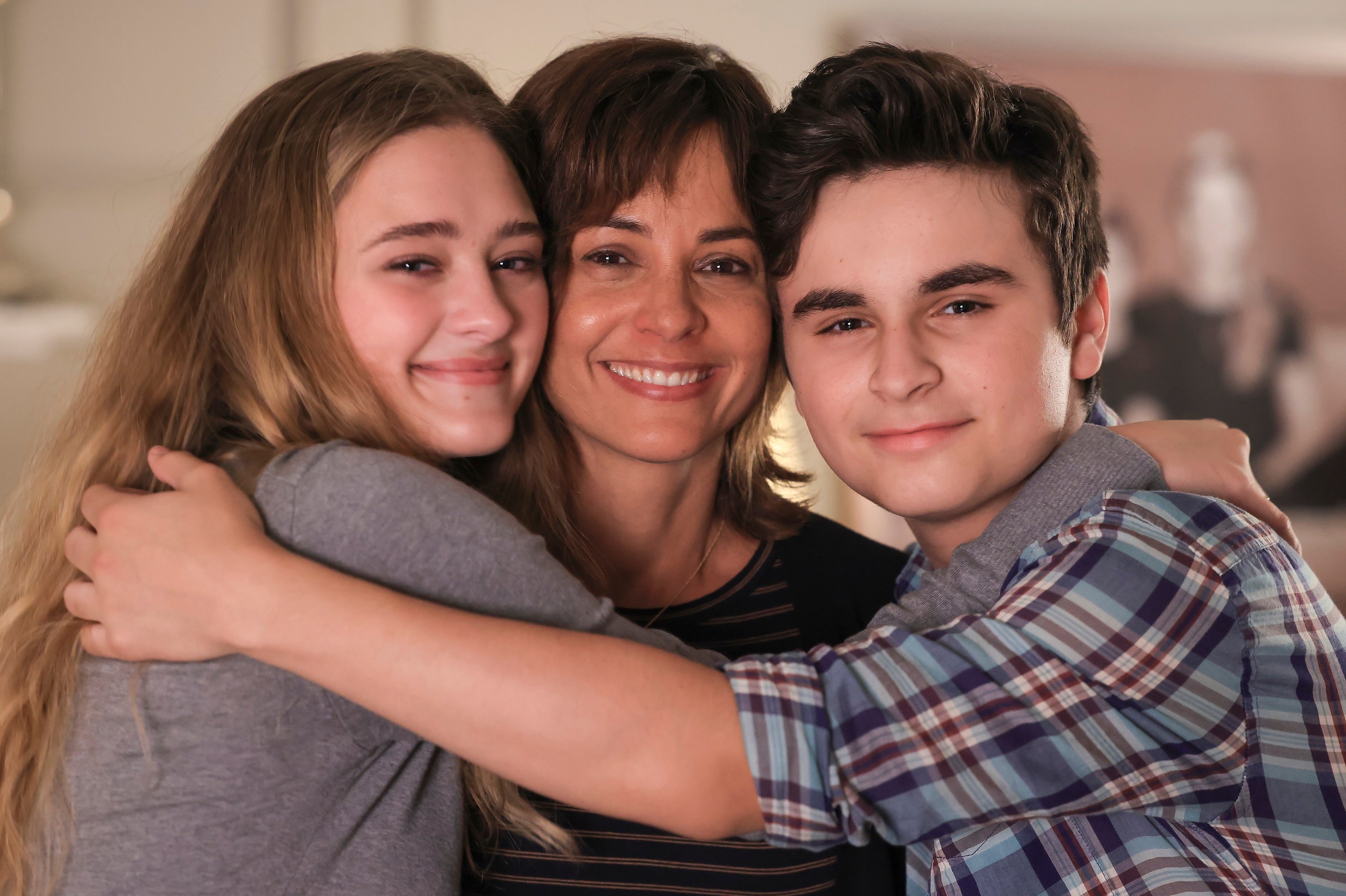 Lizzy Greene as Sophie, Stephanie Szostak as Delilah, and Chance Hurstfield as Danny hugging in an ‘A Million Little Things’ episode.
