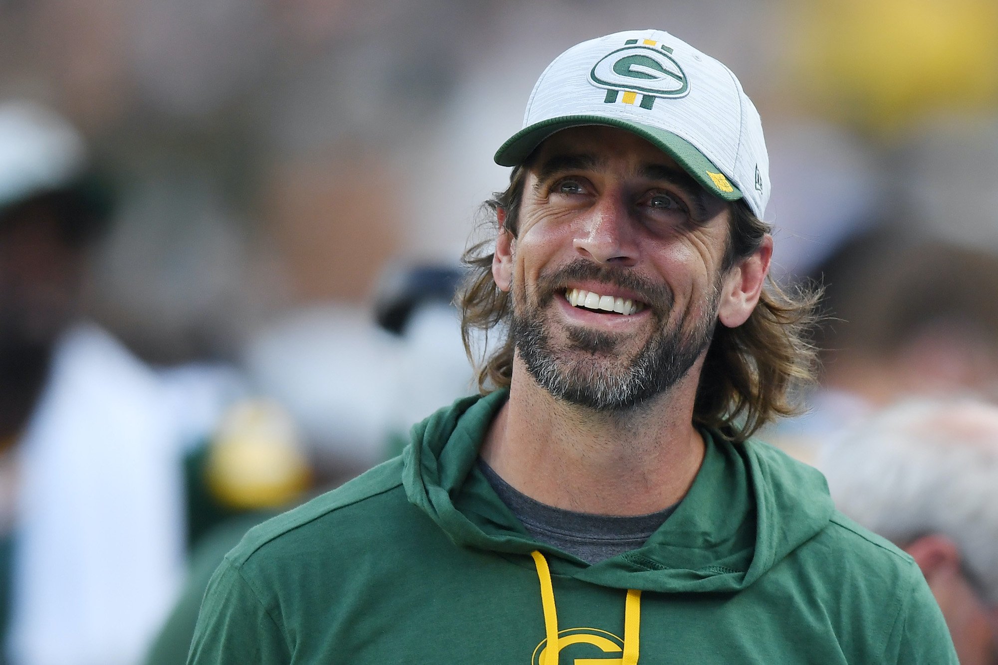 Aaron Rodgers smiling in front of a blurred crowd