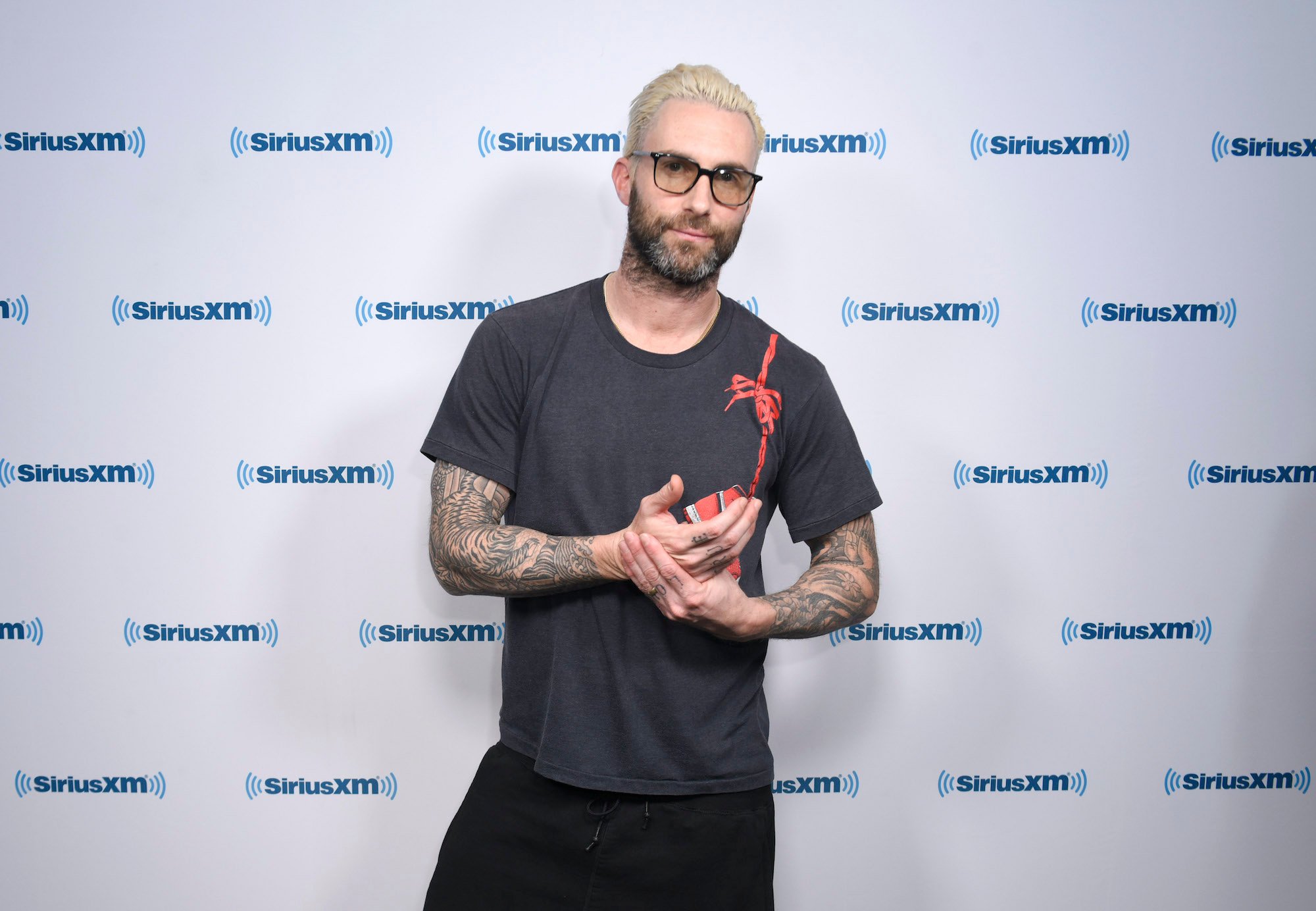 Adam Levine smiling in front of a white background