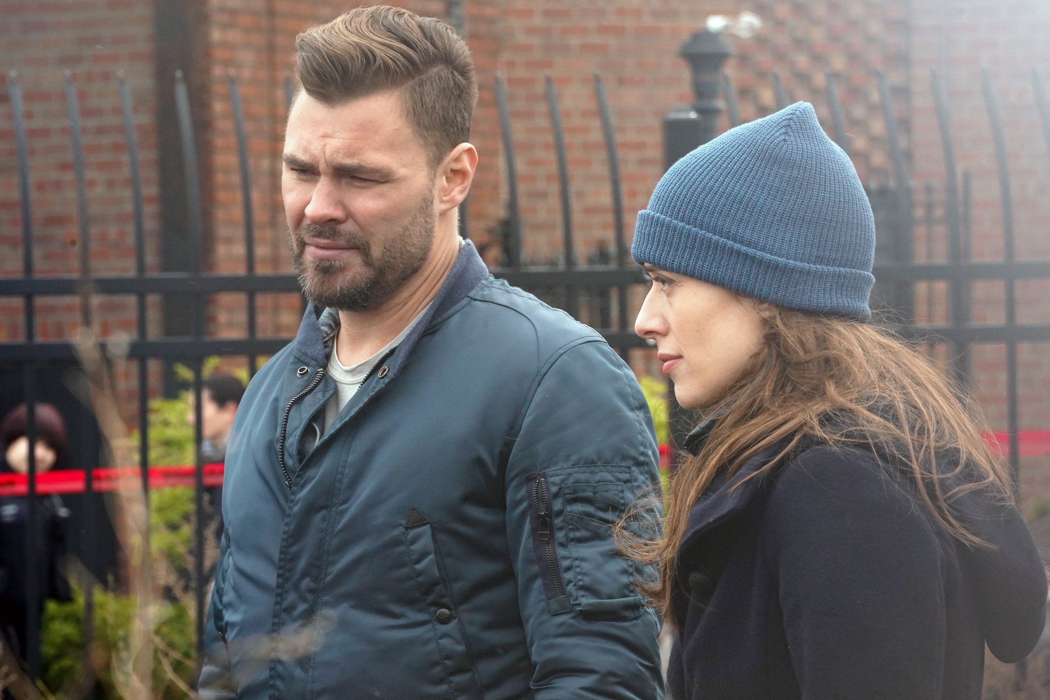 'Chicago P.D.' Season 9 cast members -- Patrick John Flueger as Adam Ruzek and Marina Squerciati as Kim Burgess standing next to each other looking serious