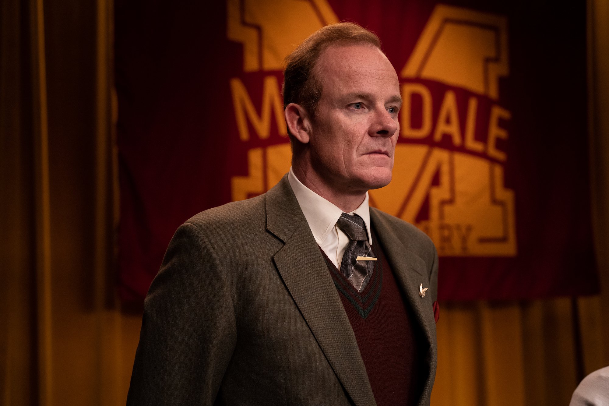 Alistair Petrie dressed in a brown suit and tie in 'Sex Education.'