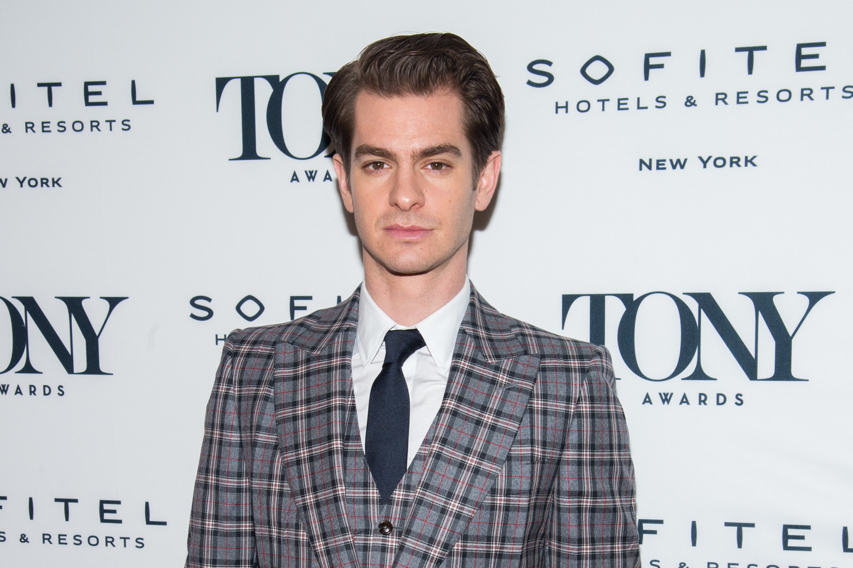 Andrew Garfield, in a grey checkered suit with a blue tie, attends the Tony Honors For Excellence in The Theater in 2018.