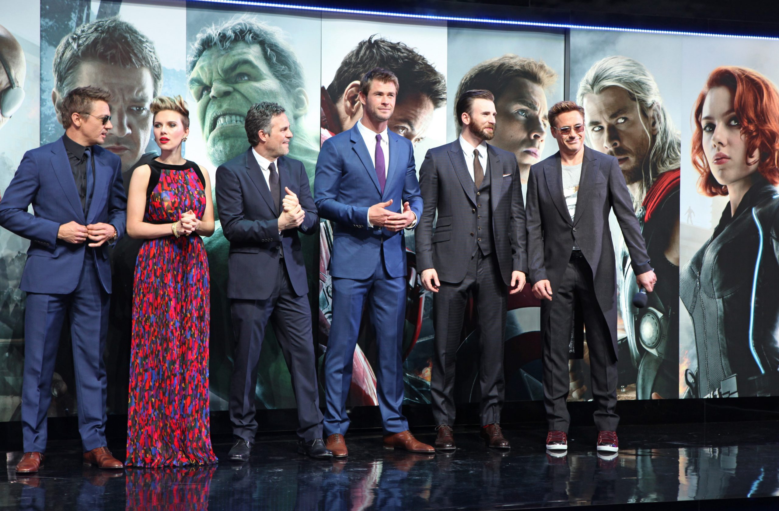 'Avengers' movies stars Jeremy Renner, Scarlett Johansson, Mark Ruffalo, Chris Hemsworth, Chris Evans, and Robert Downey Jr. They're standing in front of a wall featuring their MCU characters and all wearing formal attire.