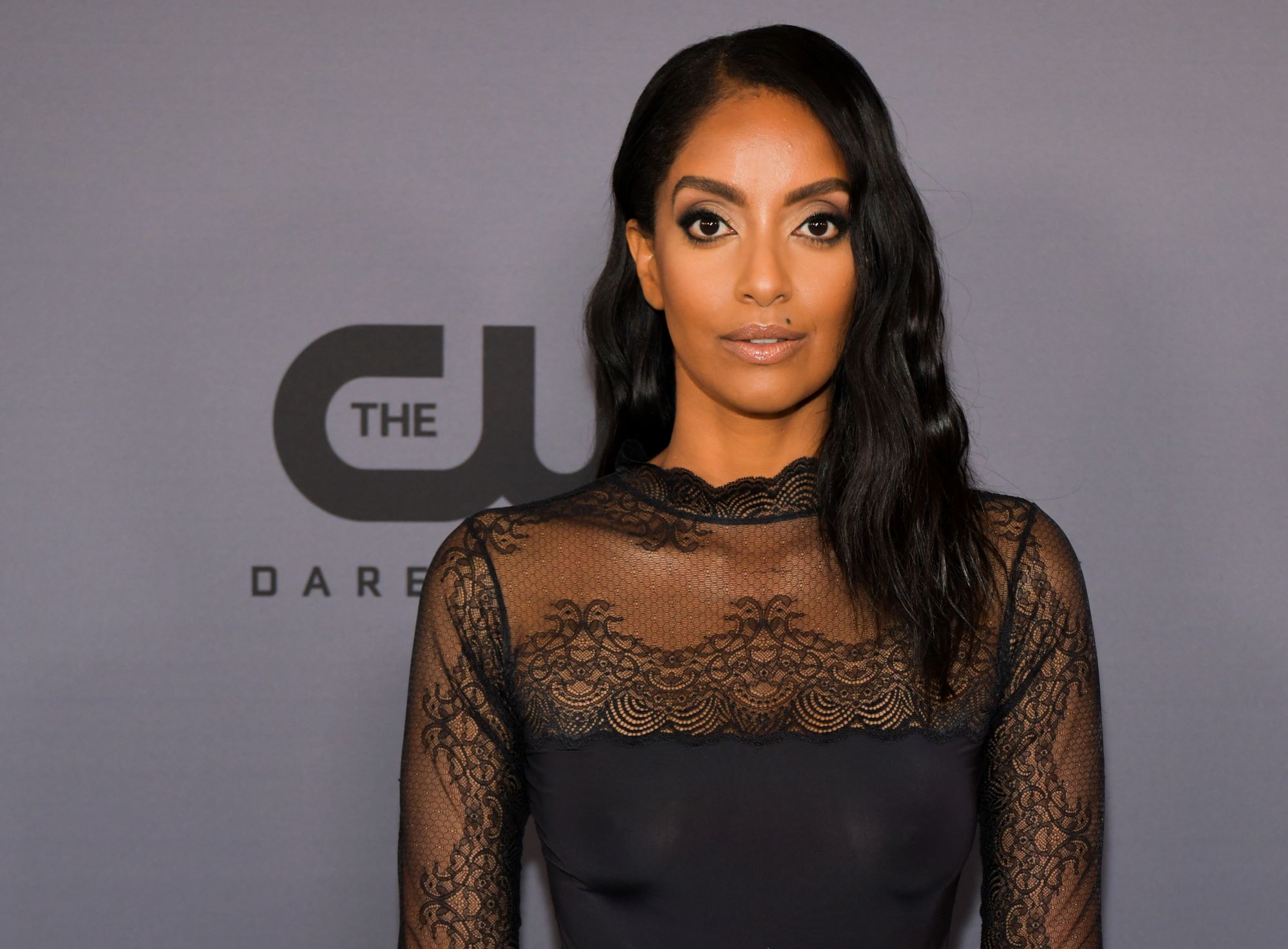 'Supergirl' actor Azie Tesfai wears a balck lace top and her hair down on the red carpet.