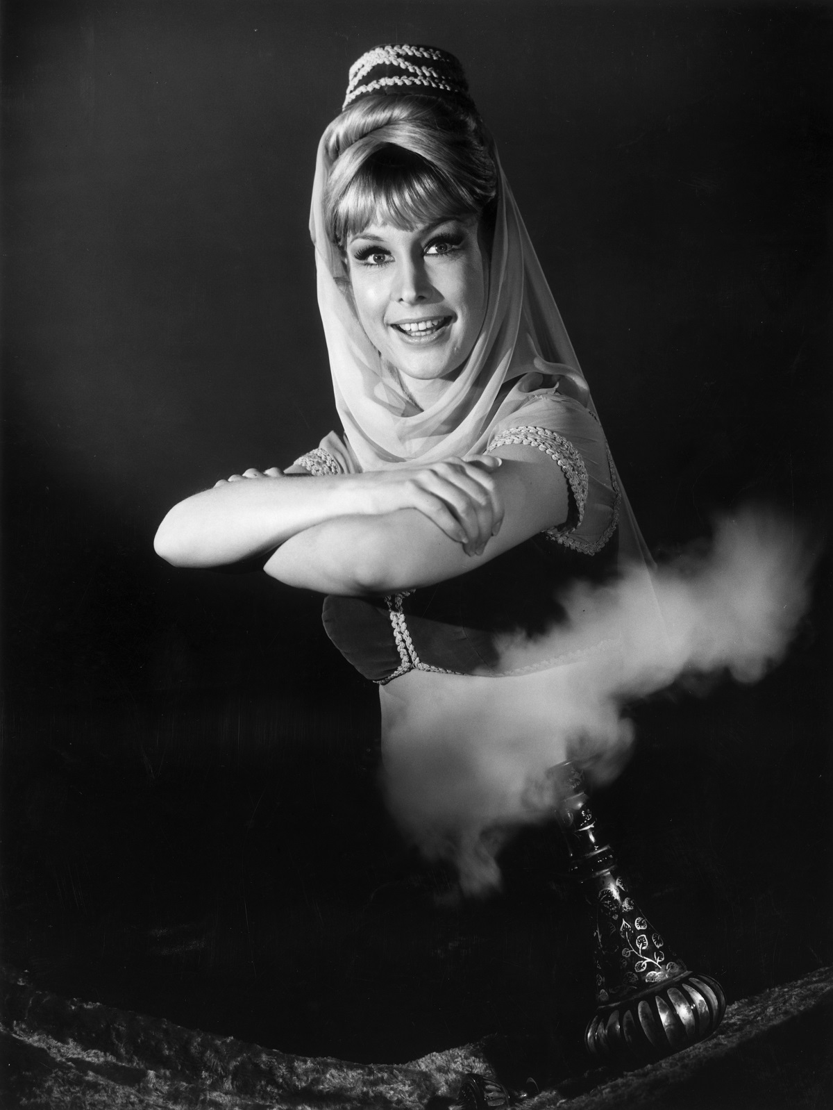 Barbara Eden rises from smoke exiting a genie bottle in a promotional portrait