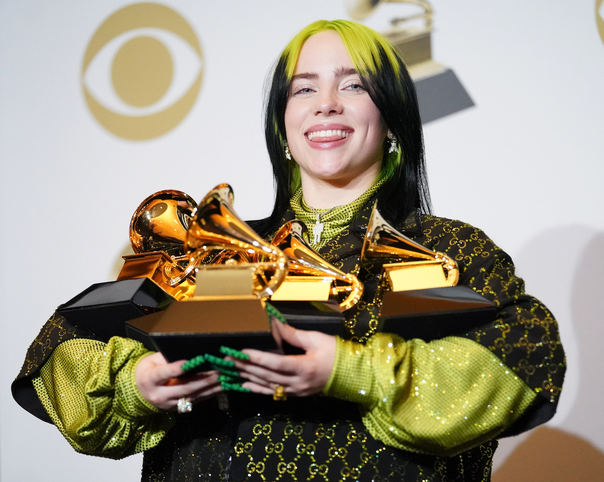 Billie Eilish holding Grammys and smiling
