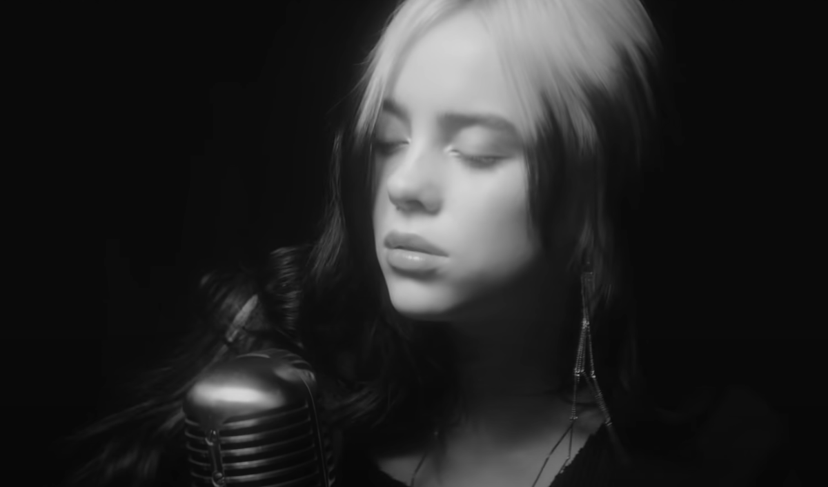 Billie Eilish in the 'No Time to Die' music video. She sings at a vintage microphone in the black-and-white music video, which features clips of Craig in past James Bond films. 'No Time to Die' is Craig's last James Bond movie, and Eilish and Finneas included a special musical tribute in their Bond song to commemorate it.