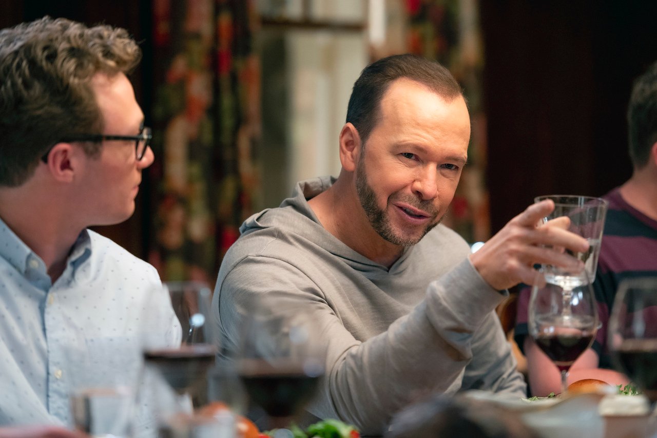 Donnie Wahlberg as Danny Reagan talks and Tony Terraciano as Jack Reagan looks at him. They sit at the dinner table on 'Blue Bloods'