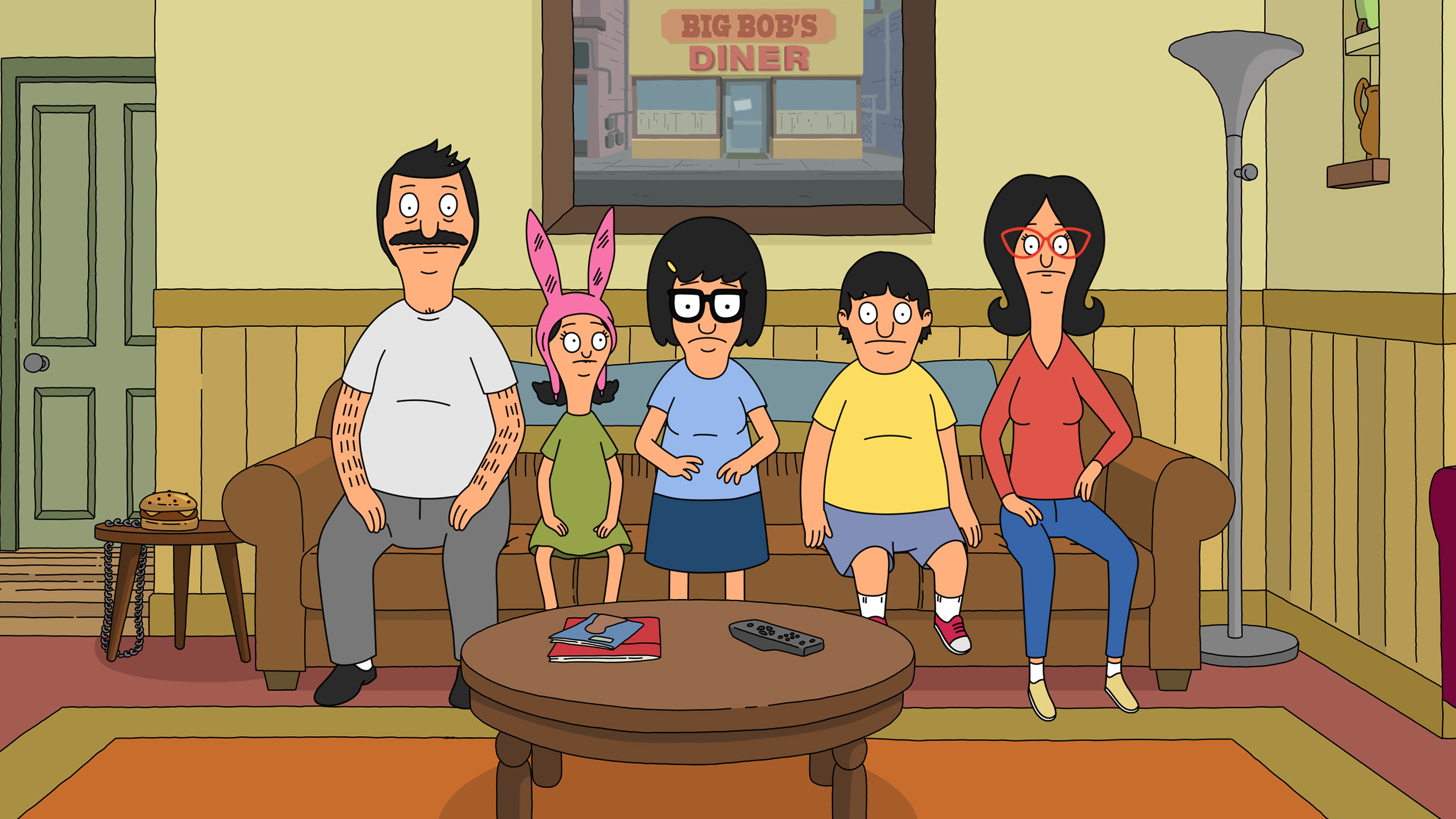 The Belcher family sits on their couch in the living room with concerned expressions on their faces in 'Bob's Burgers.'