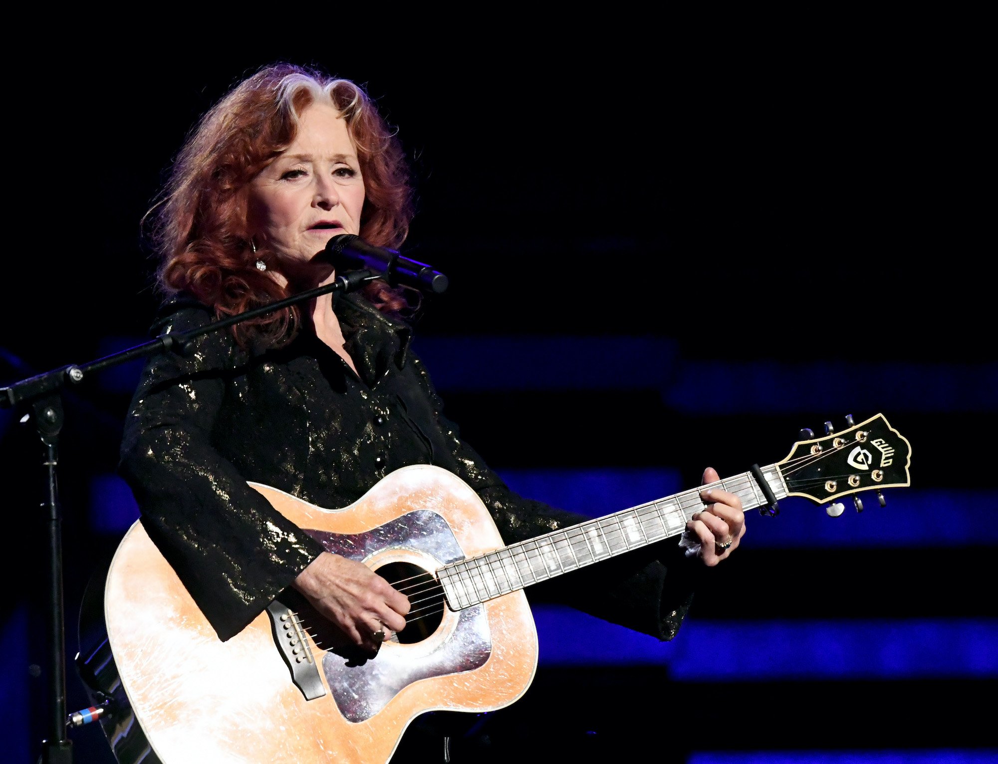 Bonnie Raitt performing, holding a guitar