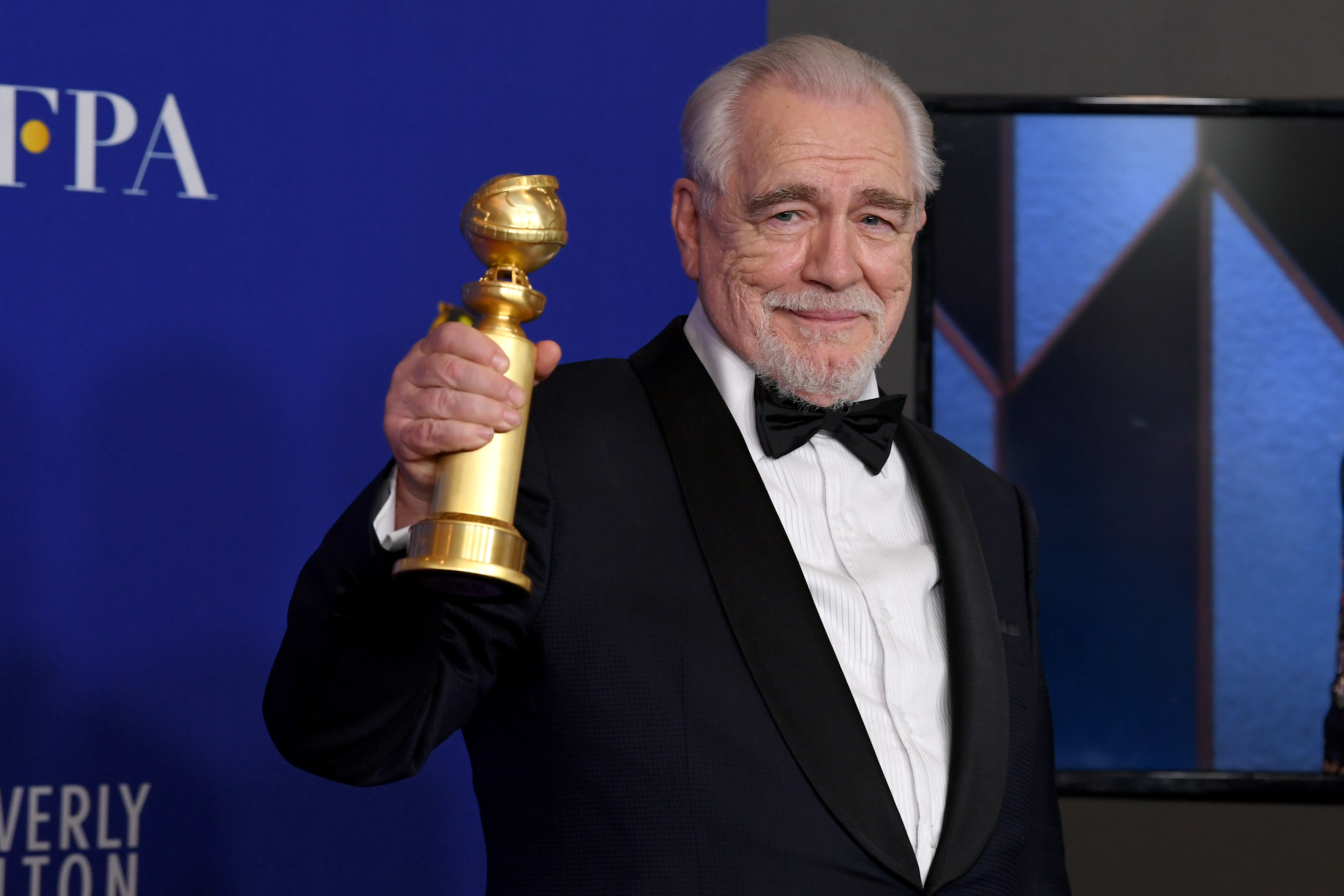 Succession cast member Brian Cox wears a tuxedo and holds a Golden Globe award.