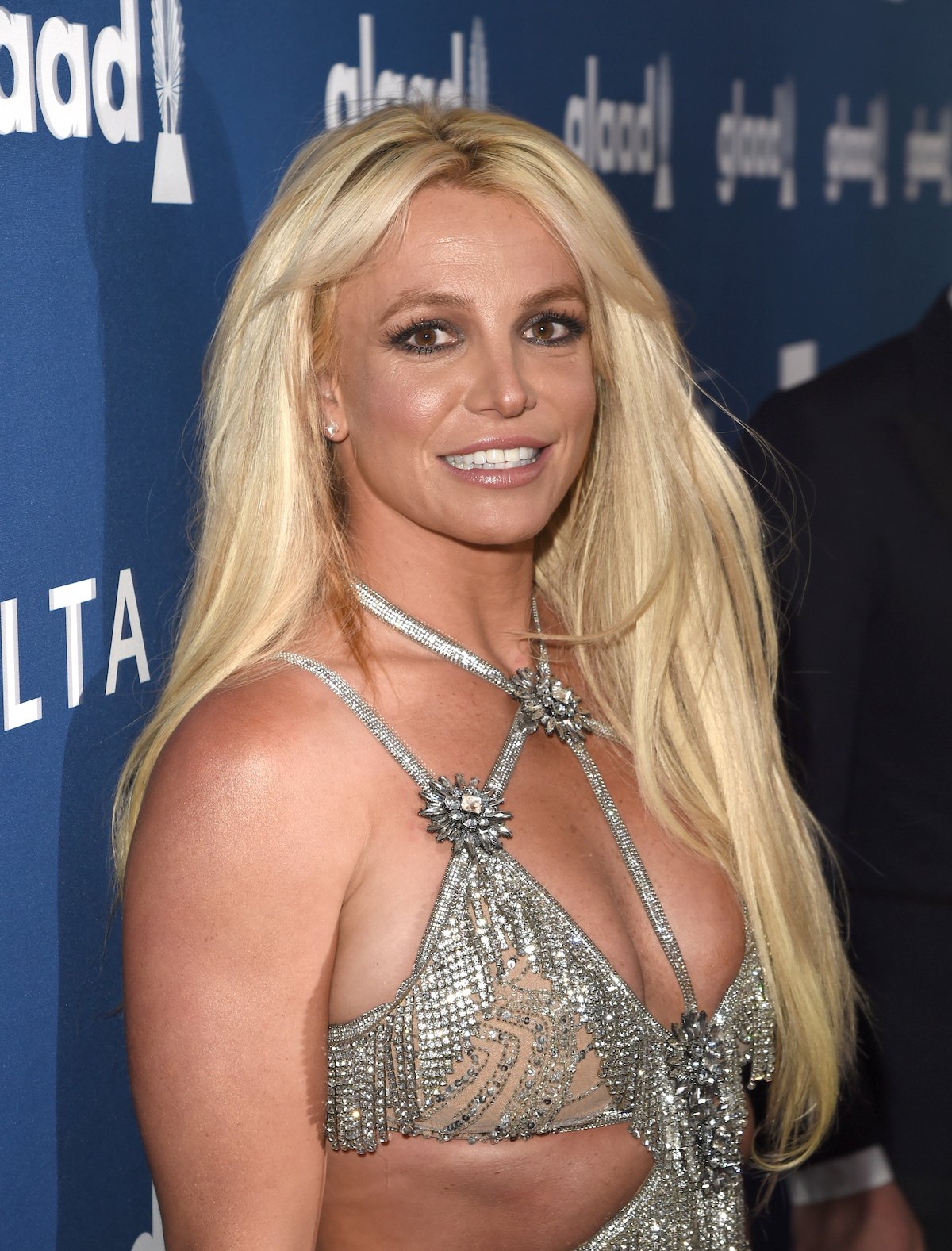 Britney Spears smiles in a sparkly silver outfit at an event.